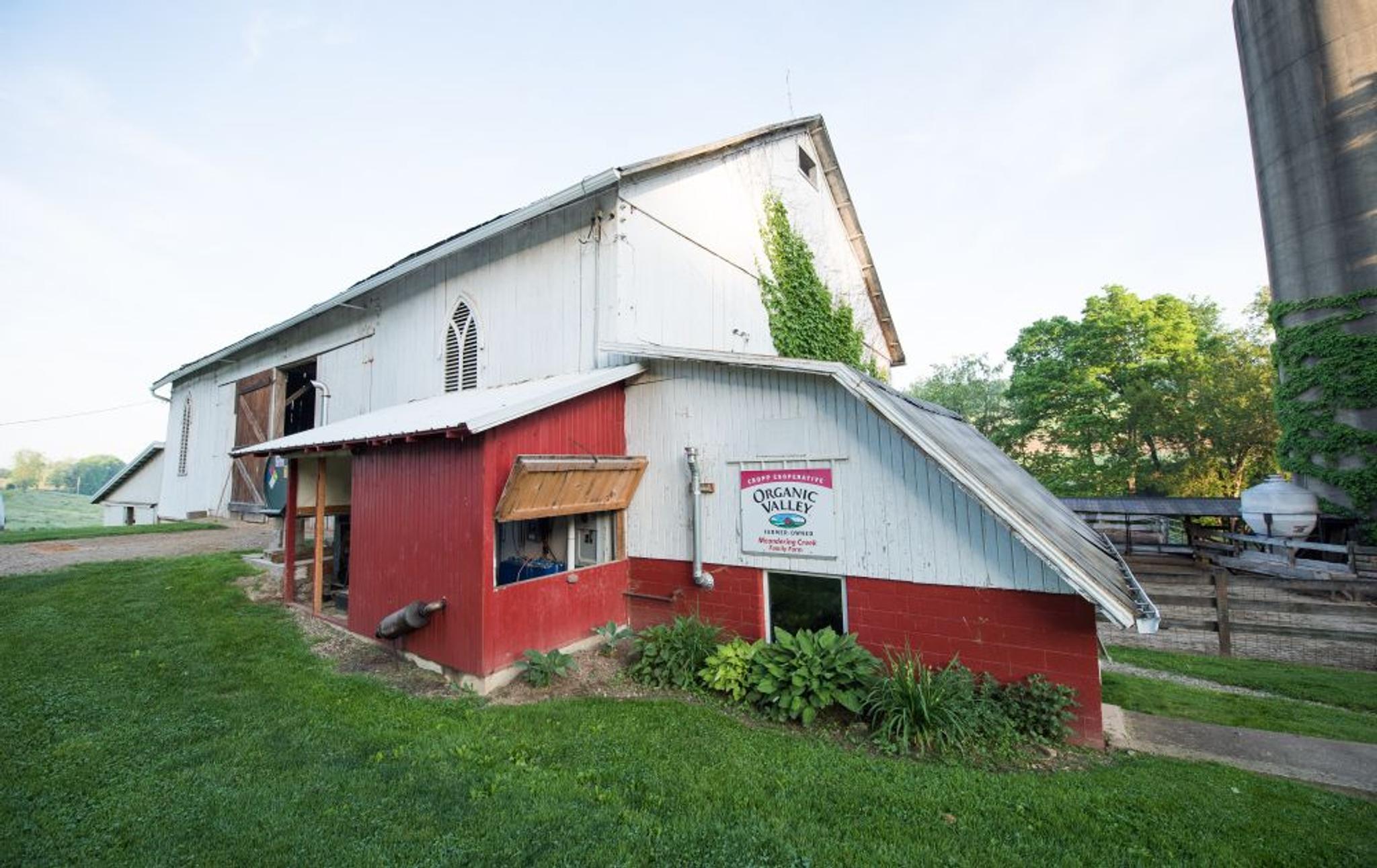 A red and white barn with an Organic Valley farmer-owned sign on it.