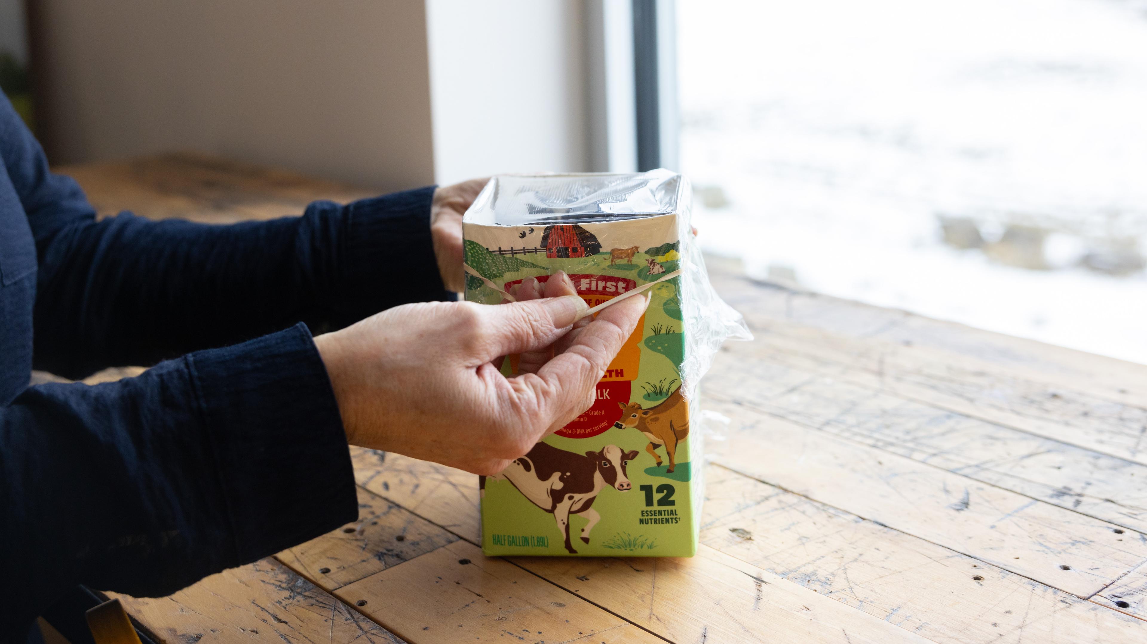 Placing plastic wrap over the carton held by a rubber band makes an ideal growing environment.