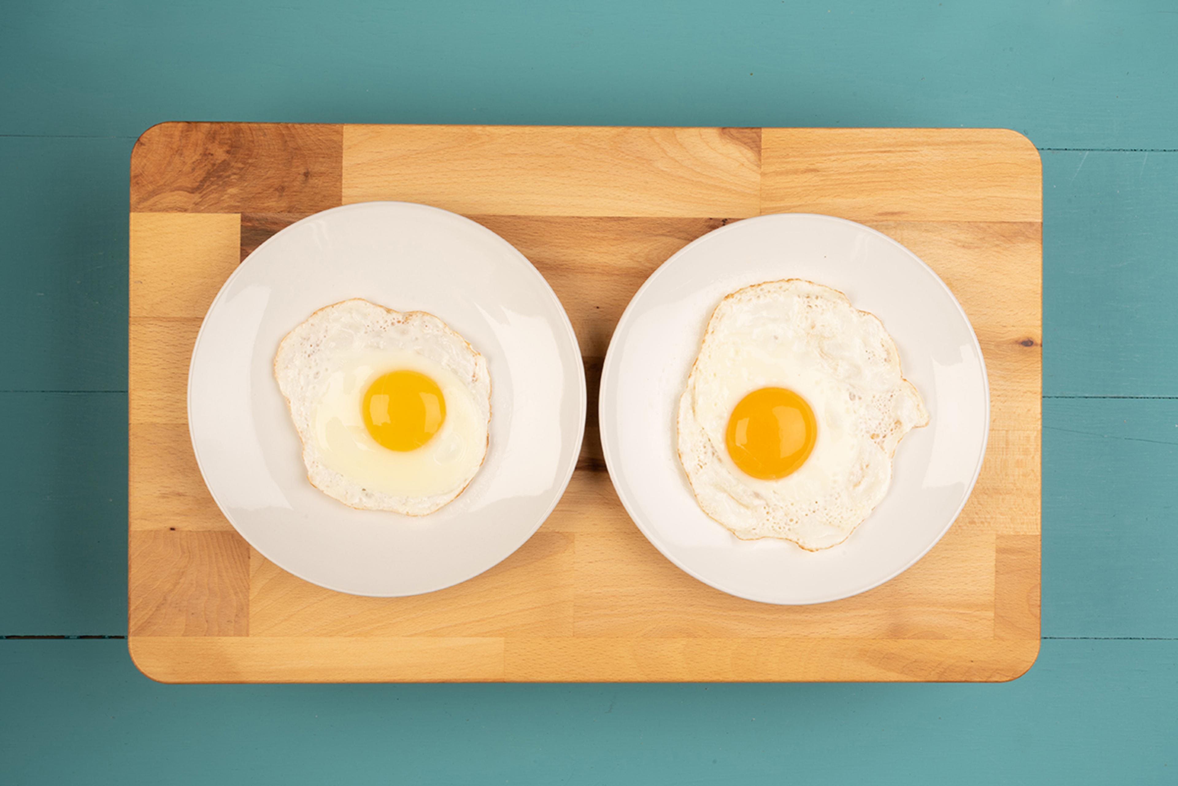 Two fried eggs on plates with different yolk colors.