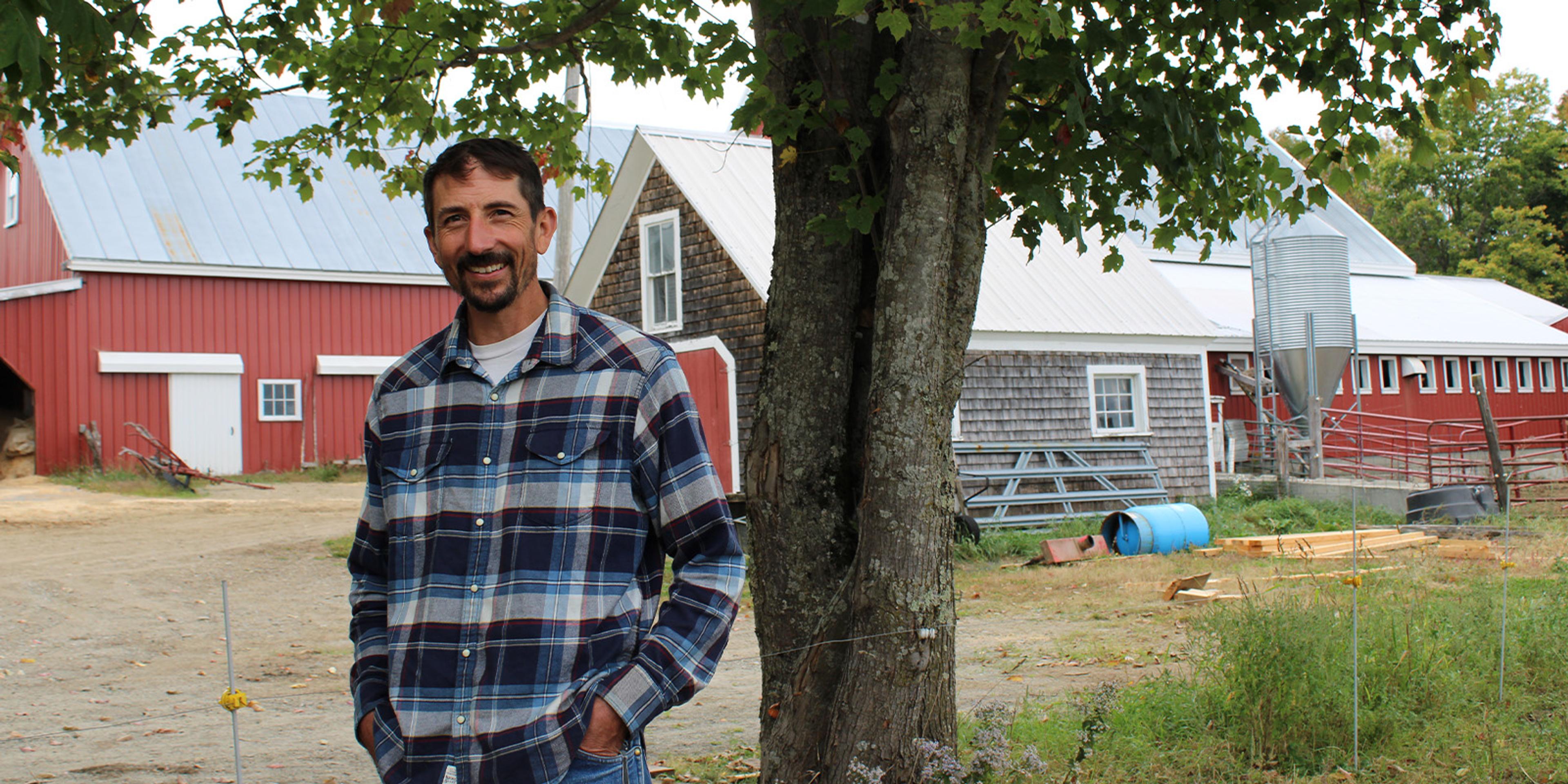 Stephen Dolan stands in front of barns.