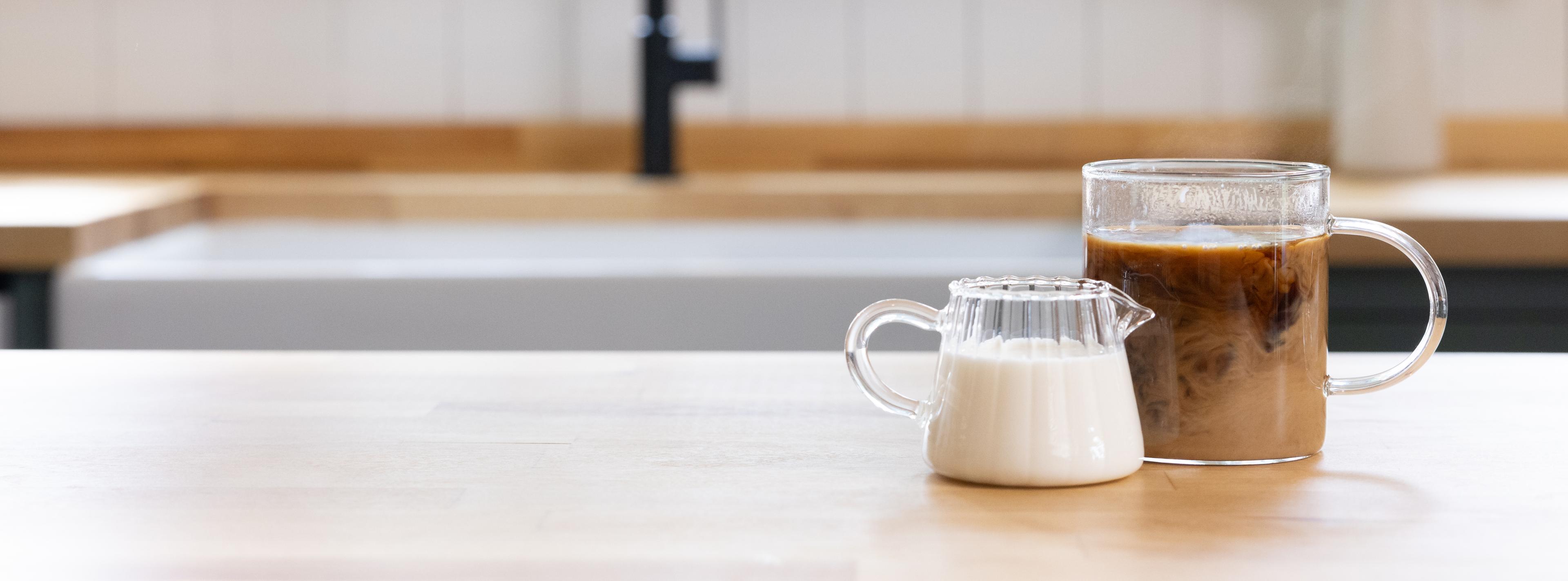 A cup or cream and a cup of coffee.