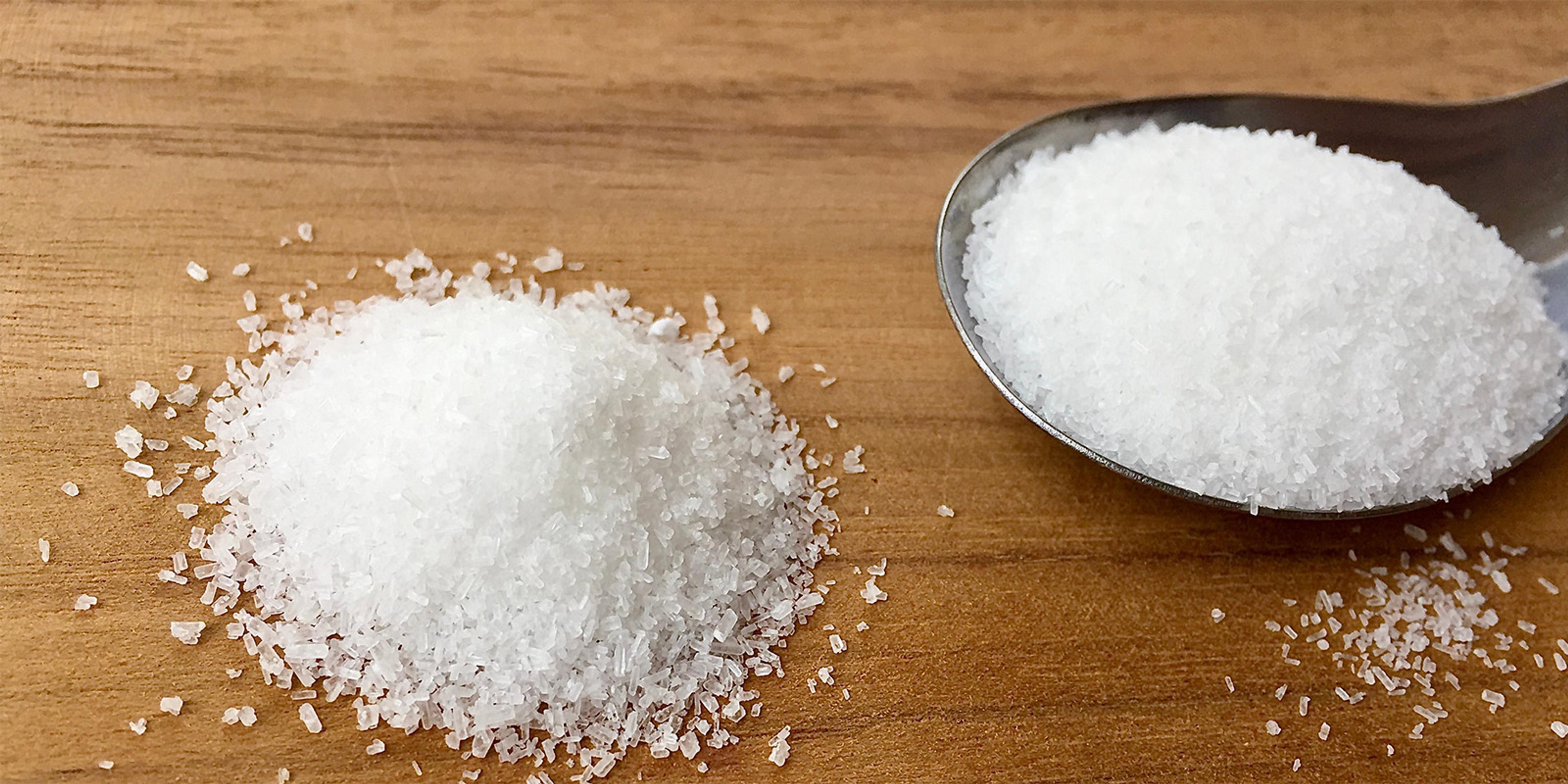 A spoonful of salt on a table.