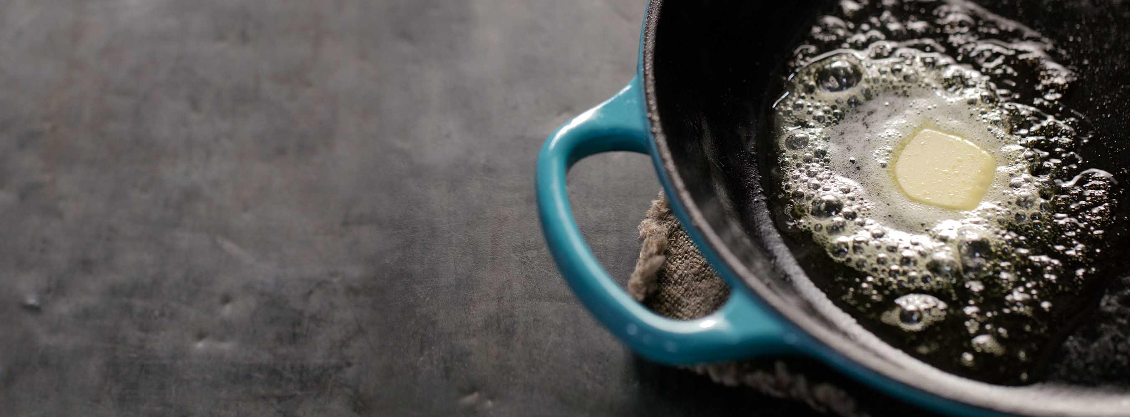 A blue pan with a slice of butter melting in it. 