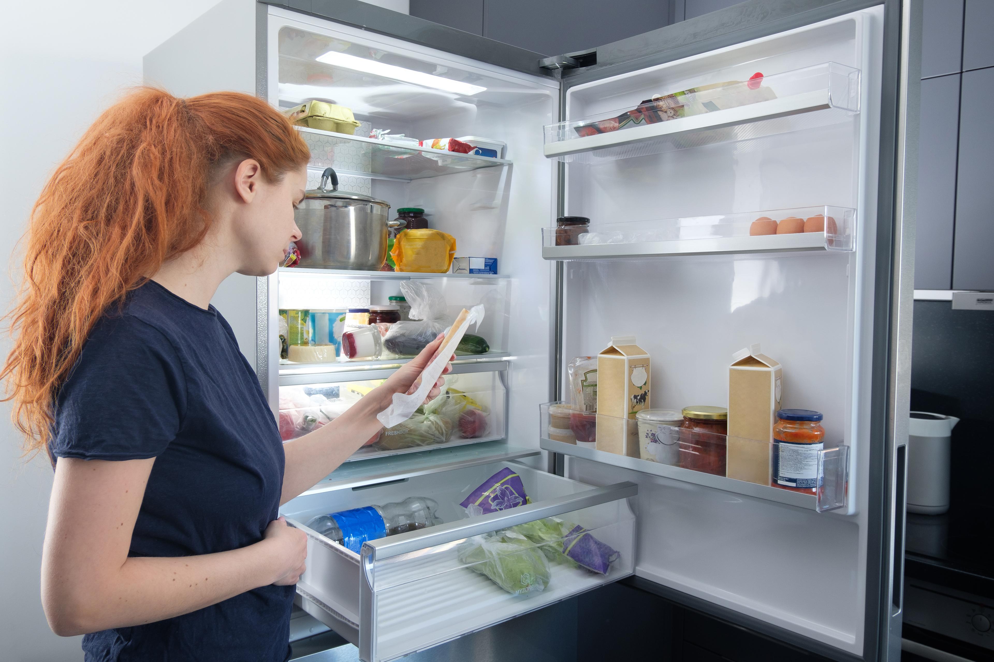 A woman looks in a refrigerator.