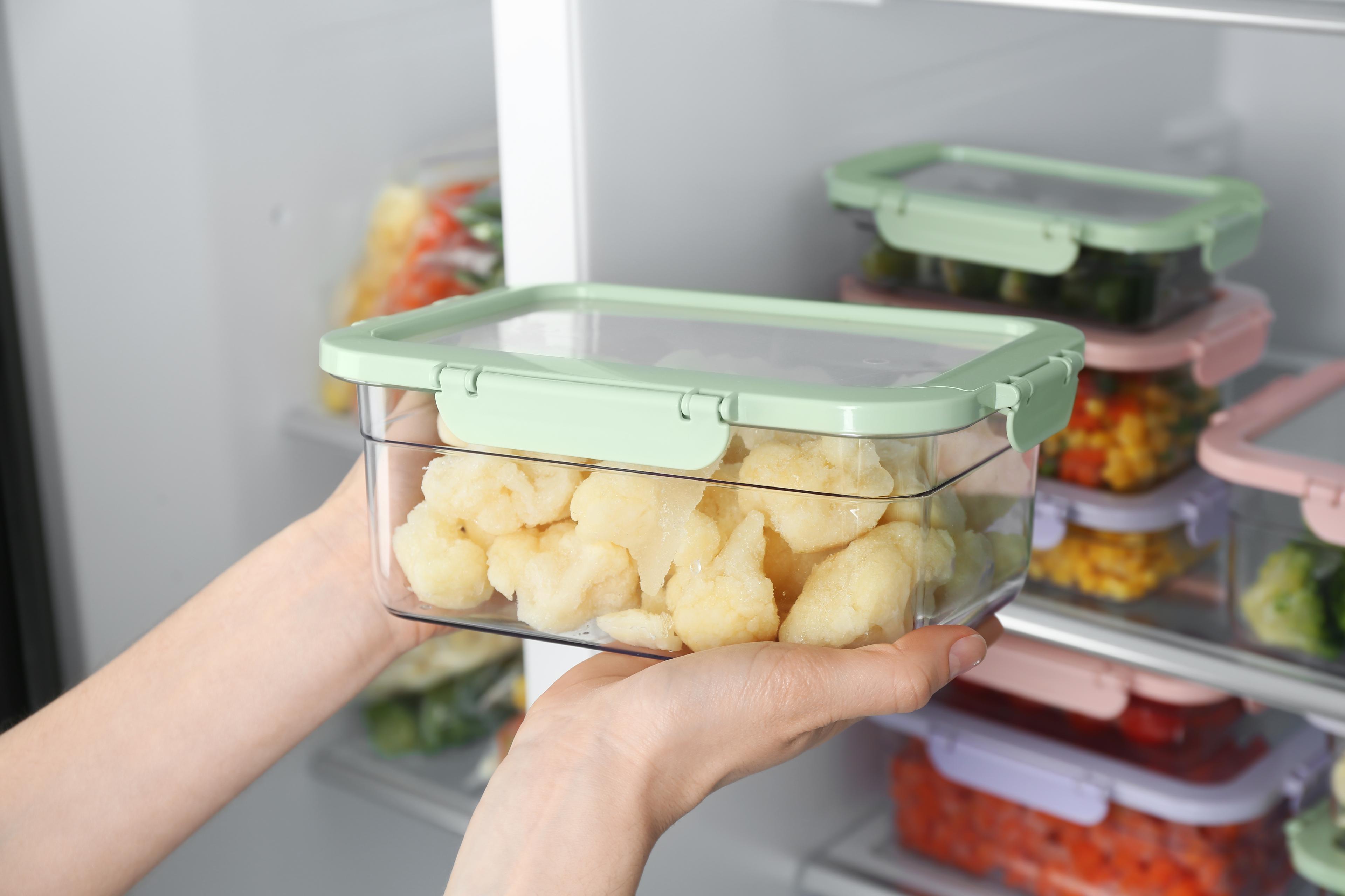 A woman takes a container out of the fridge.