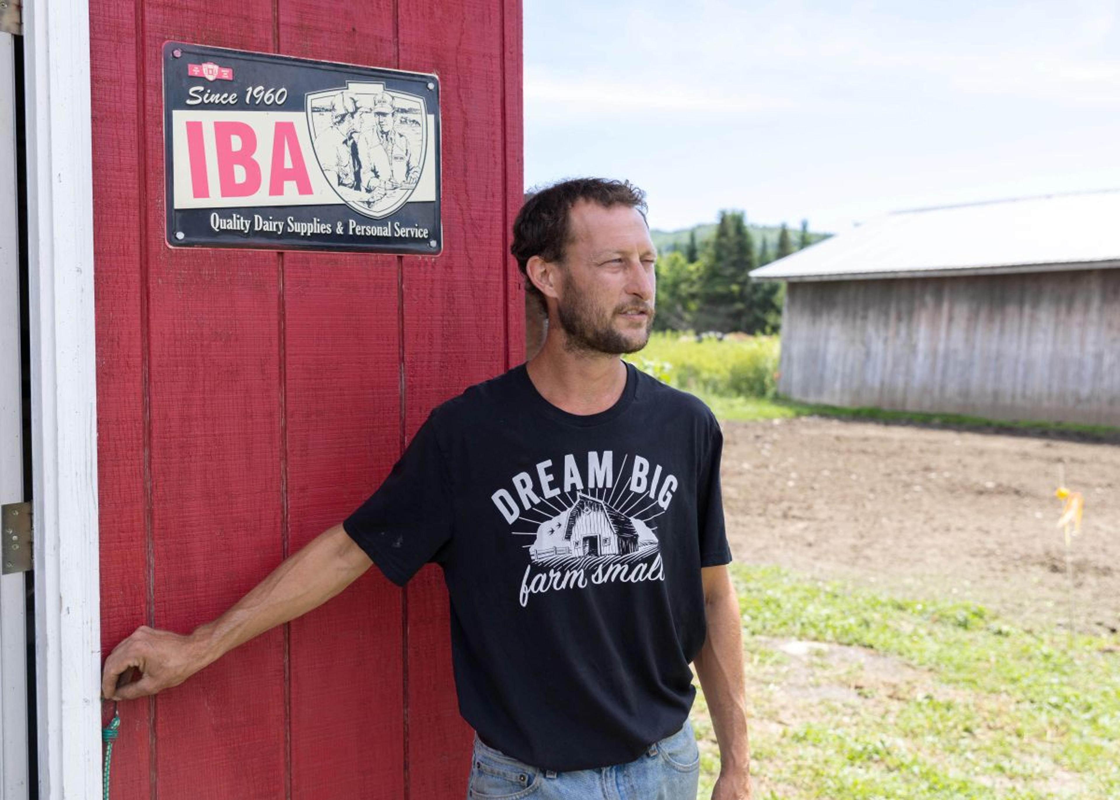 Patrick Bedard leans on a red barn at his Vermont farm.