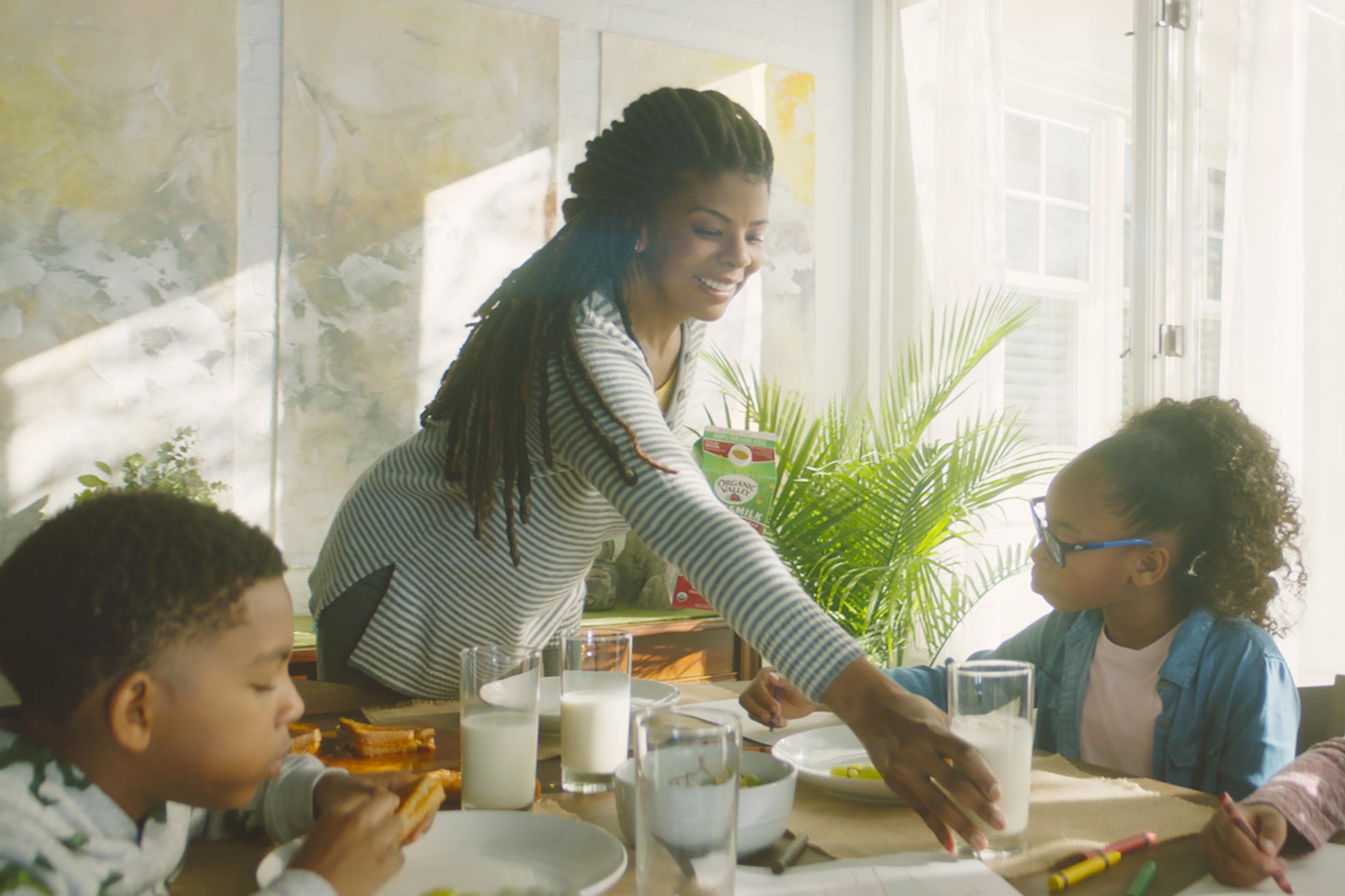 Mom serves her kids glasses of organic milk at the dinner table.