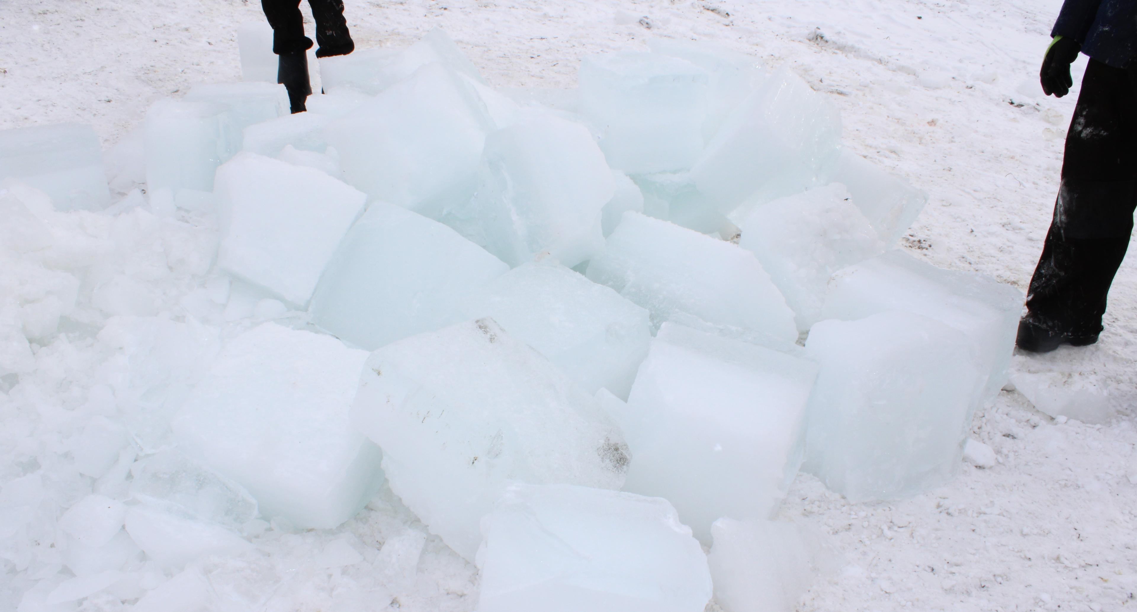 Men stand by a pile of ice blocks.