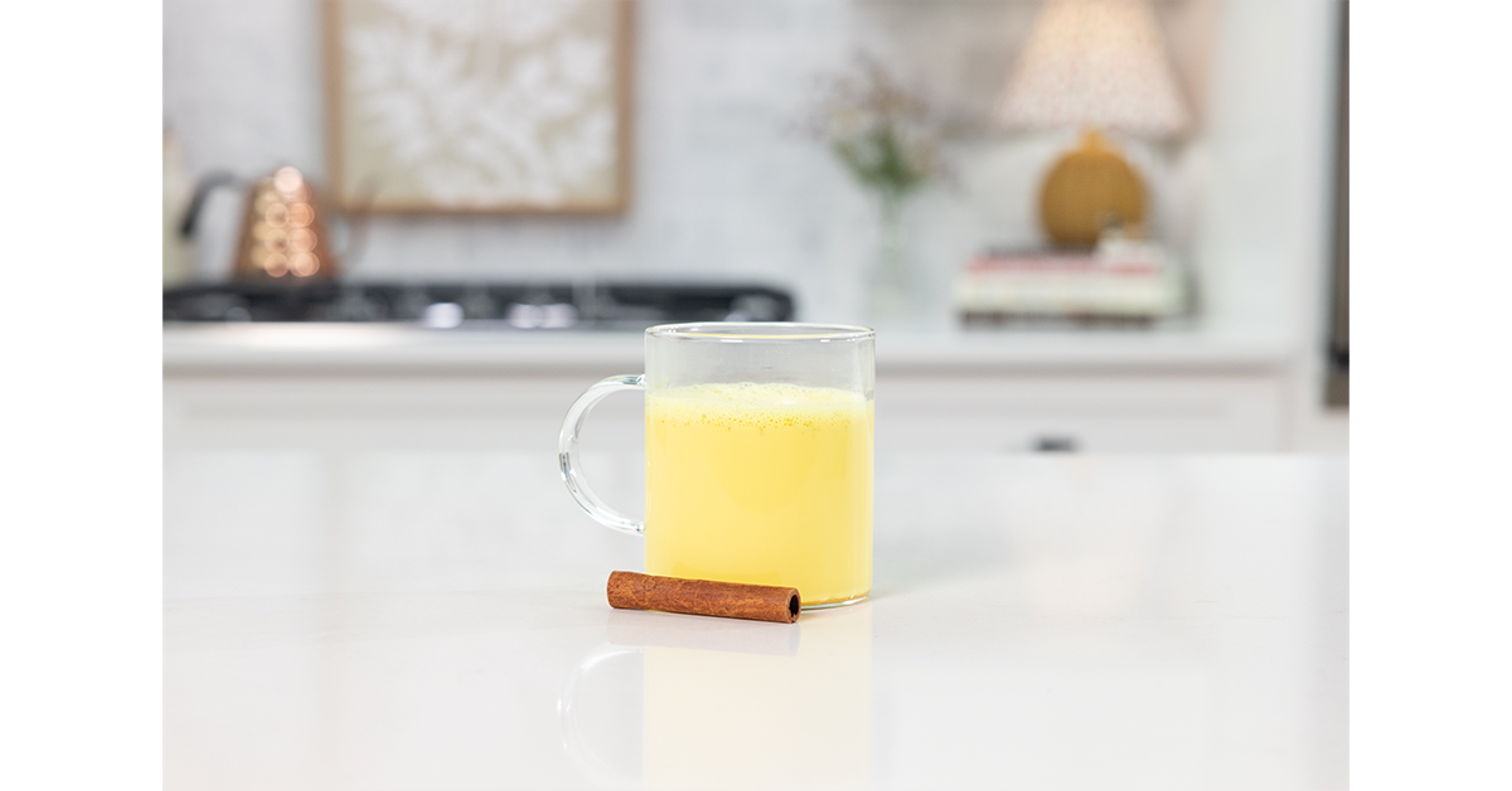 Golden milk on a counter with a cinnamon stick.