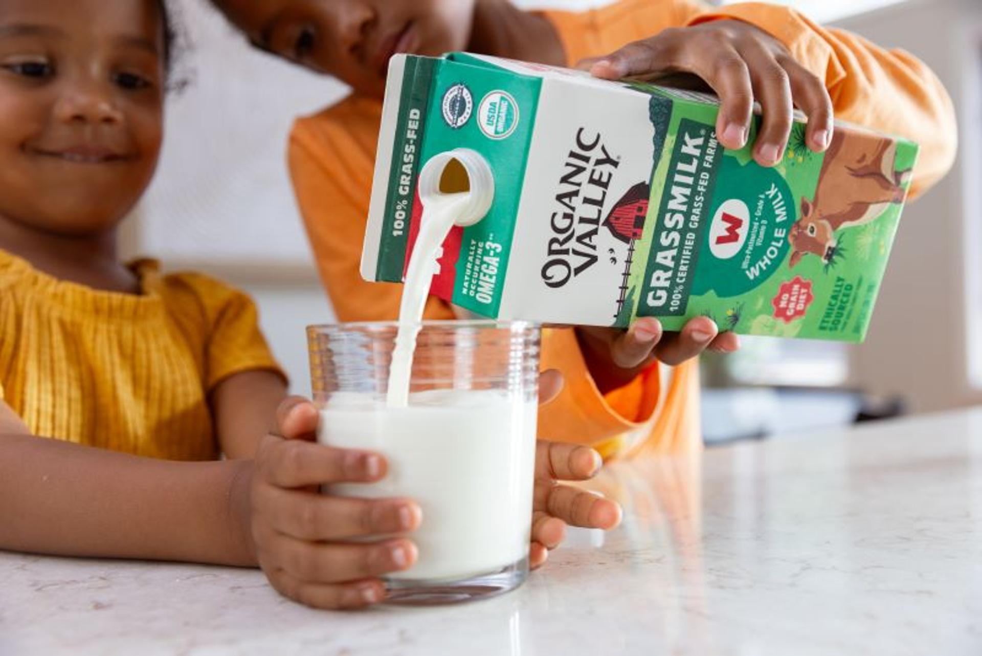 Brother pours little sister a glass of organic Grassmilk.