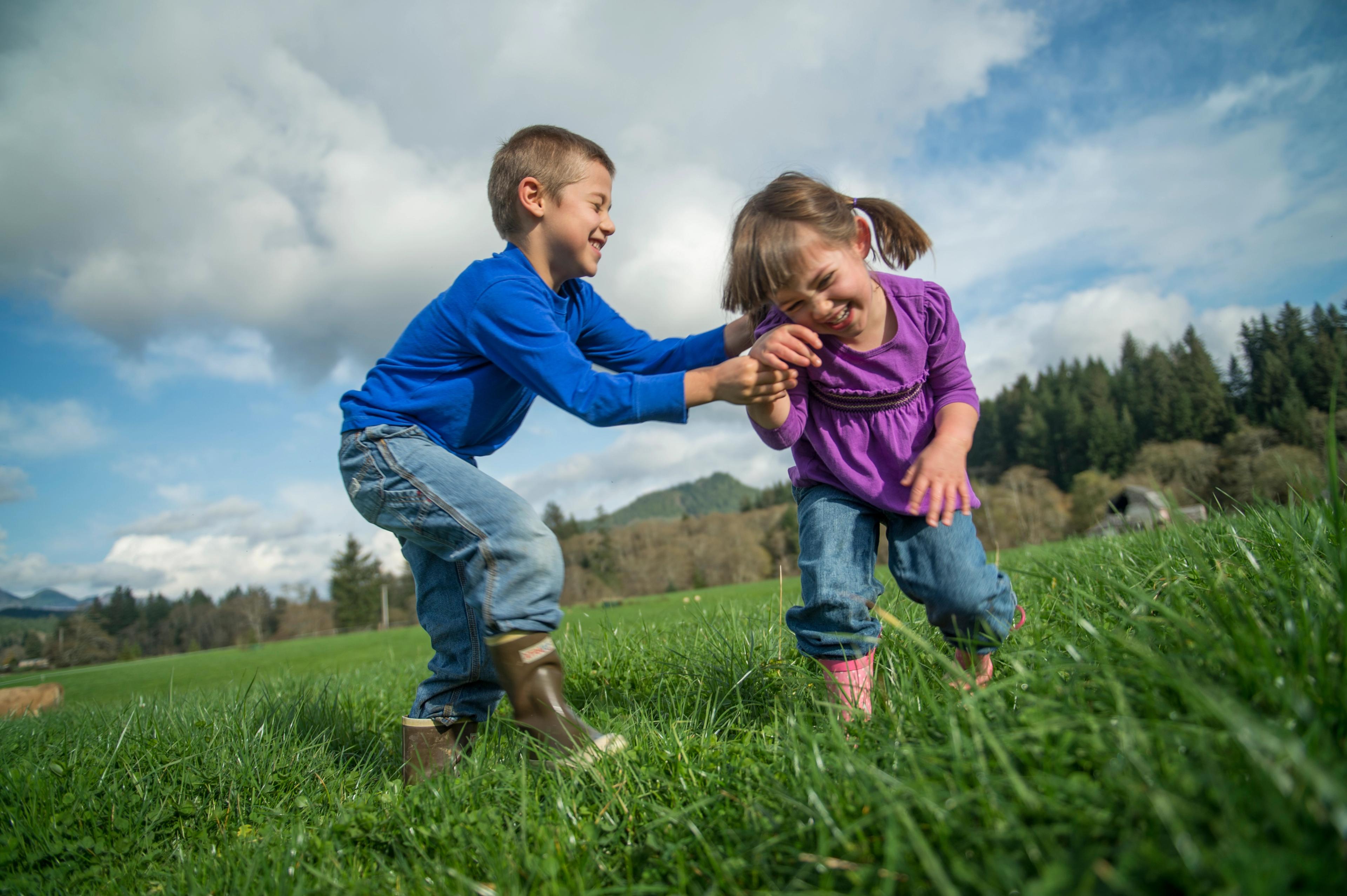 Two children playing together in the grass.