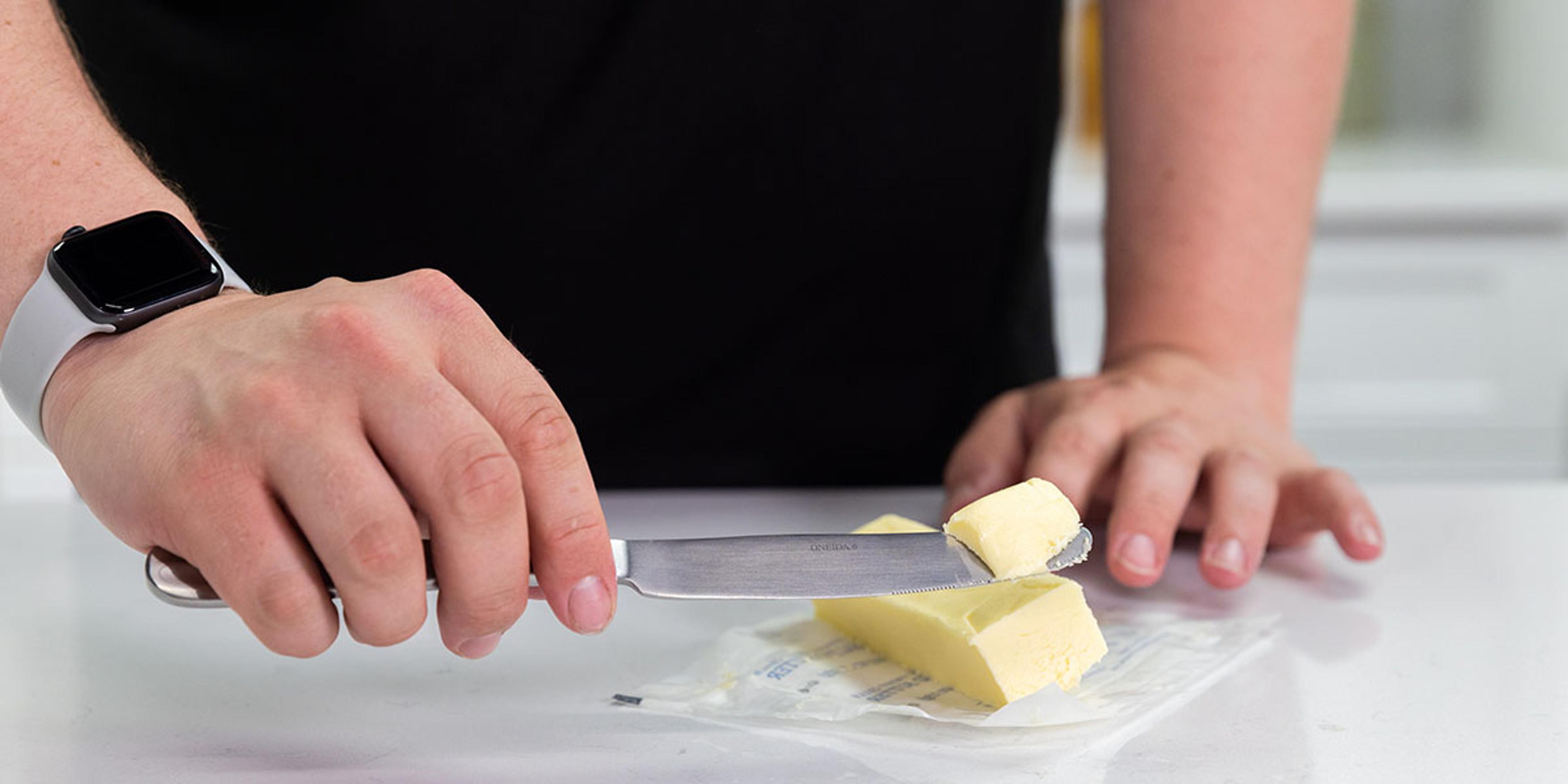 A man cuts organic butter with a knife.