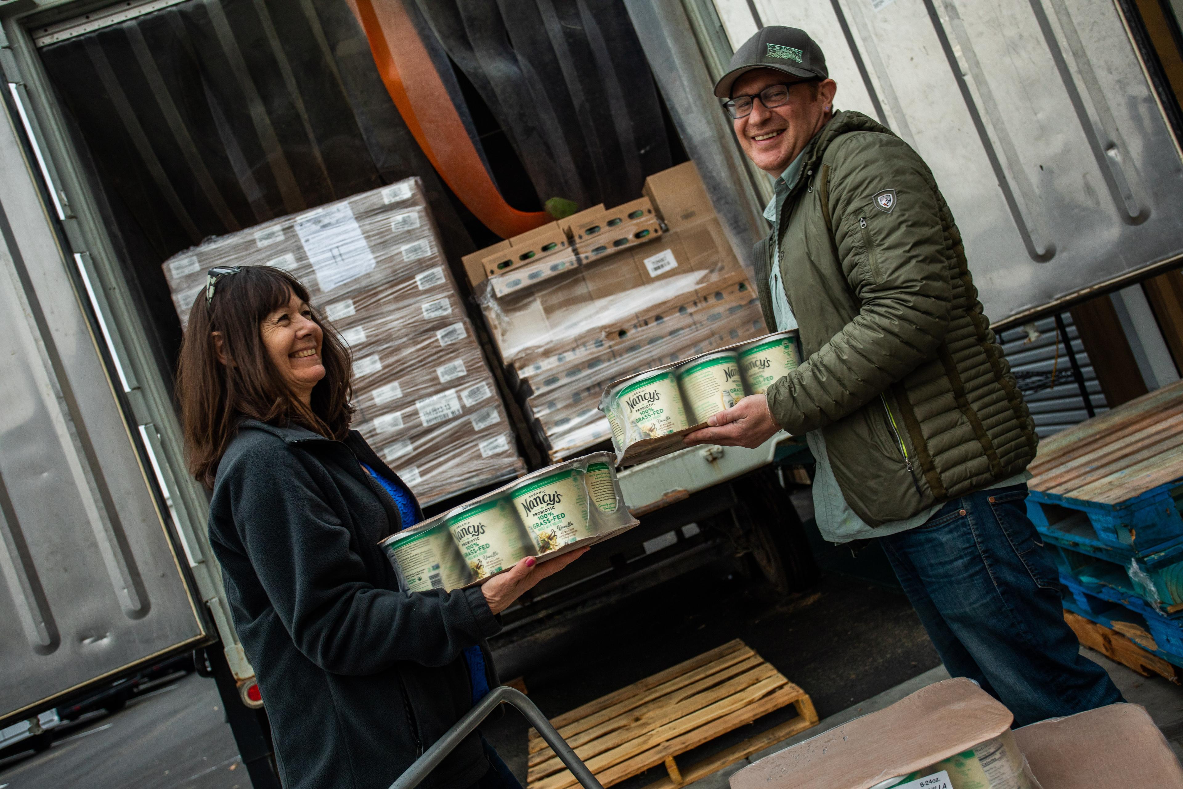 A man and a woman smile as they unload Nancy’s yogurt from a delivery truck.