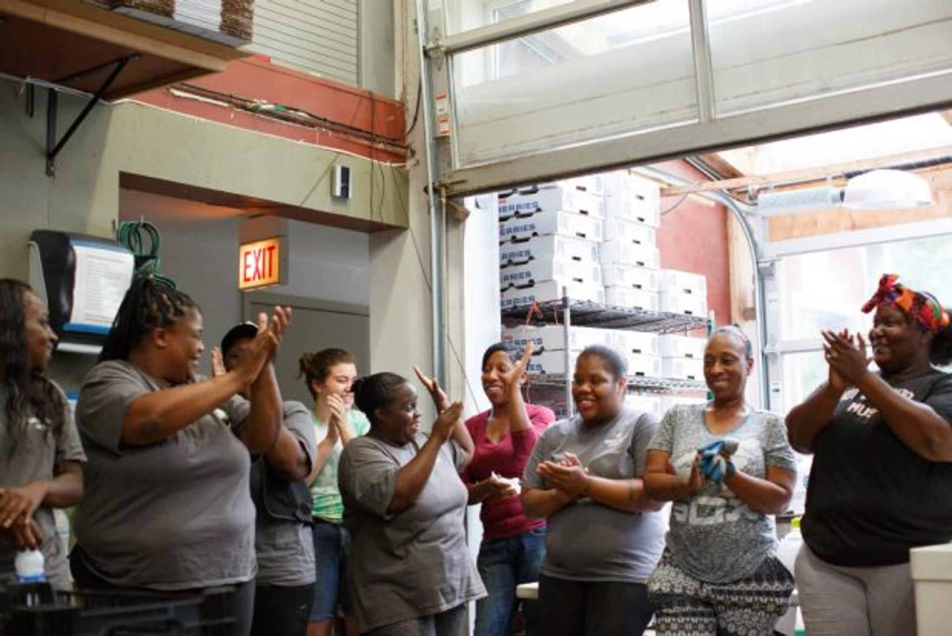 Women with Growing Home clap while standing in a loading dock.