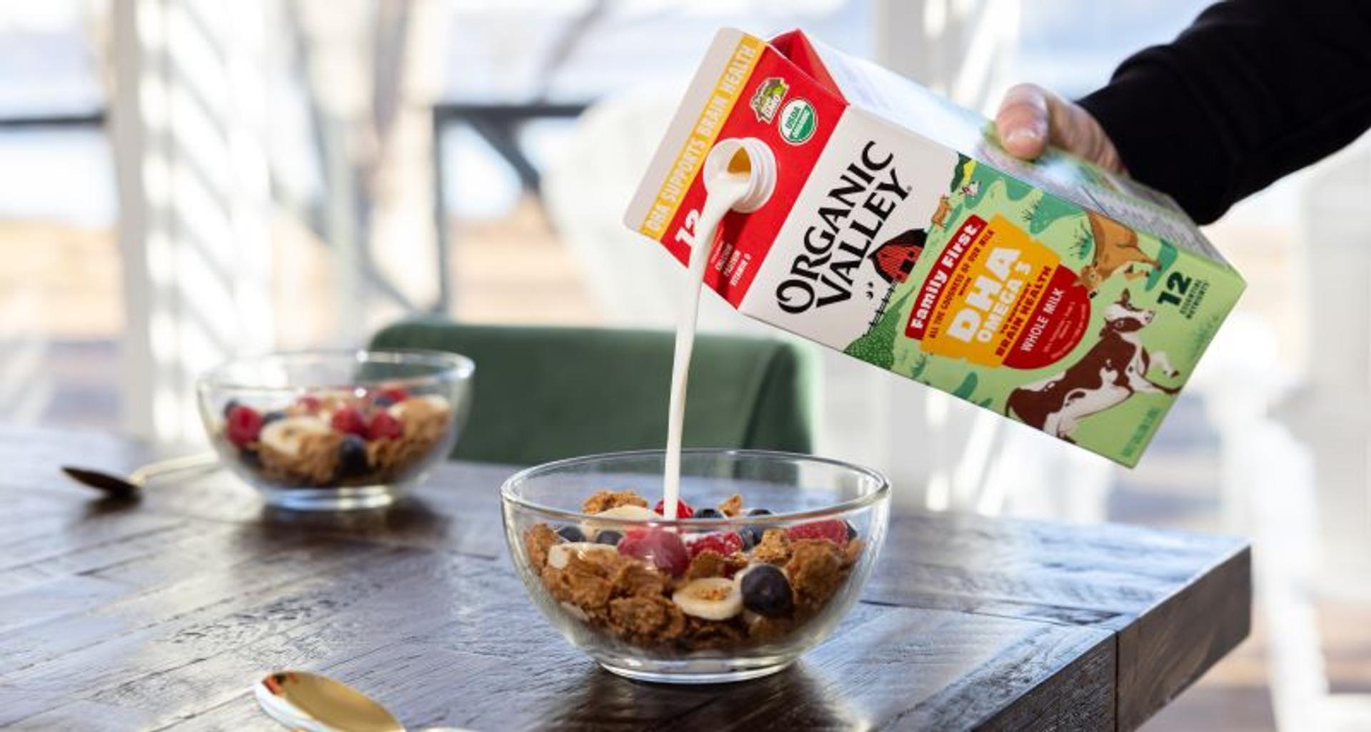 Organic milk being poured into a bowl of cereal.