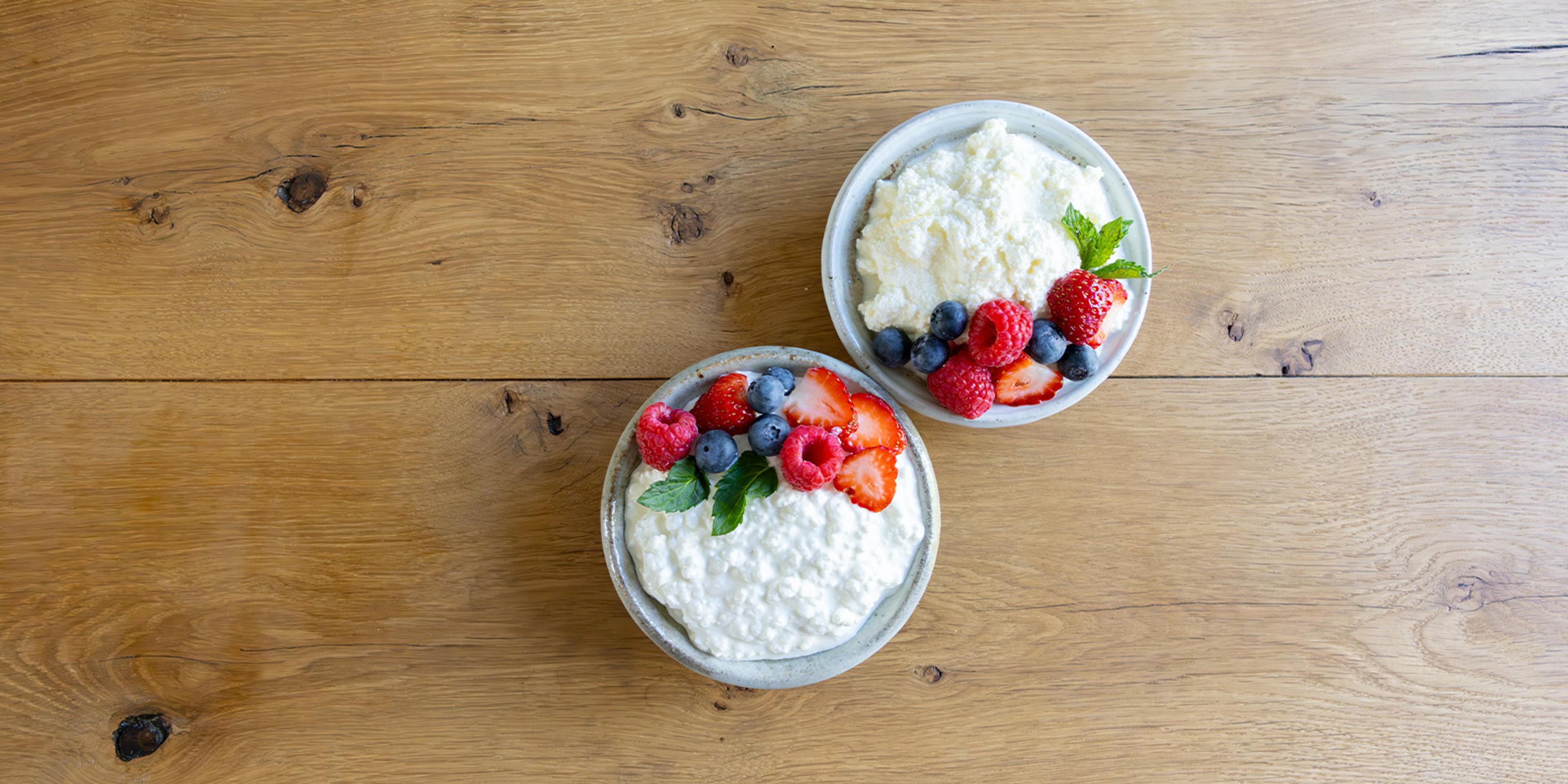 A bowl of organic cottage cheese and organic ricotta cheeses with fruit on a table.
