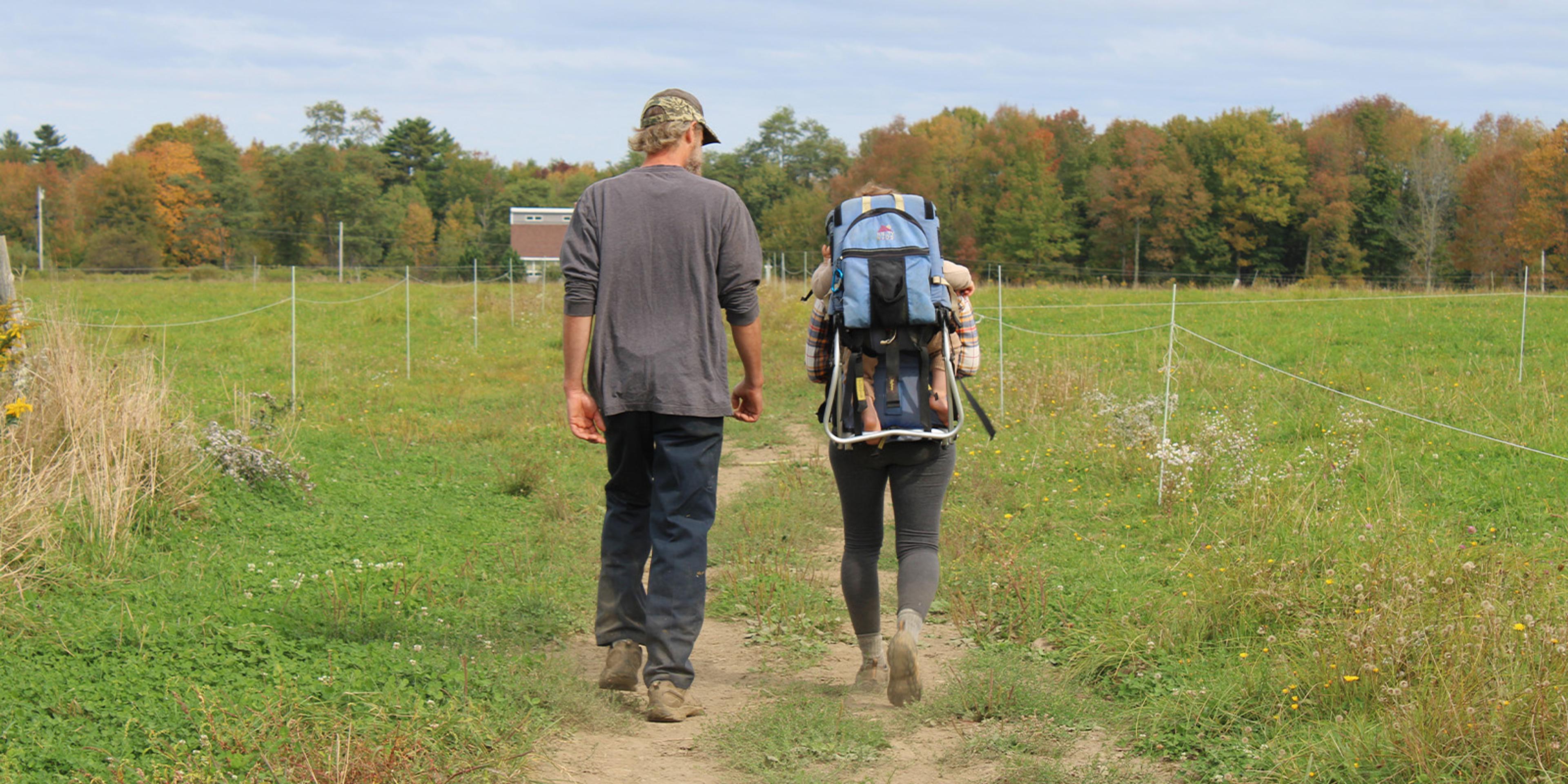 Three family members walk down a worn lane between fences. 