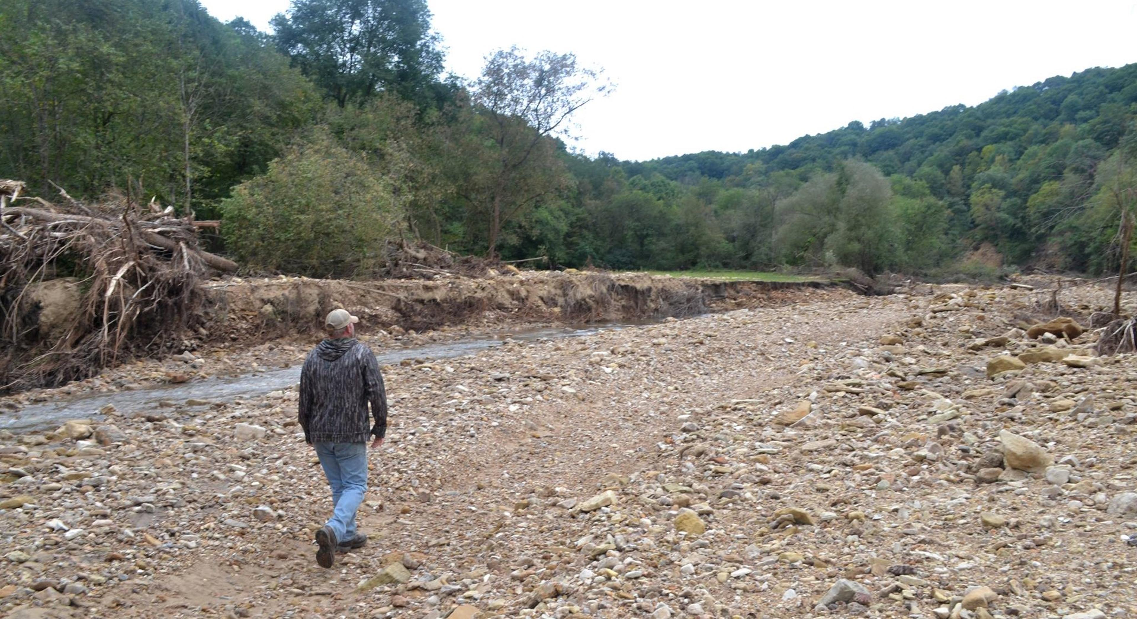 Tucker Gretebeck walks over rocks and rubble in an area impacted by flooding on his Wisconsin farm.