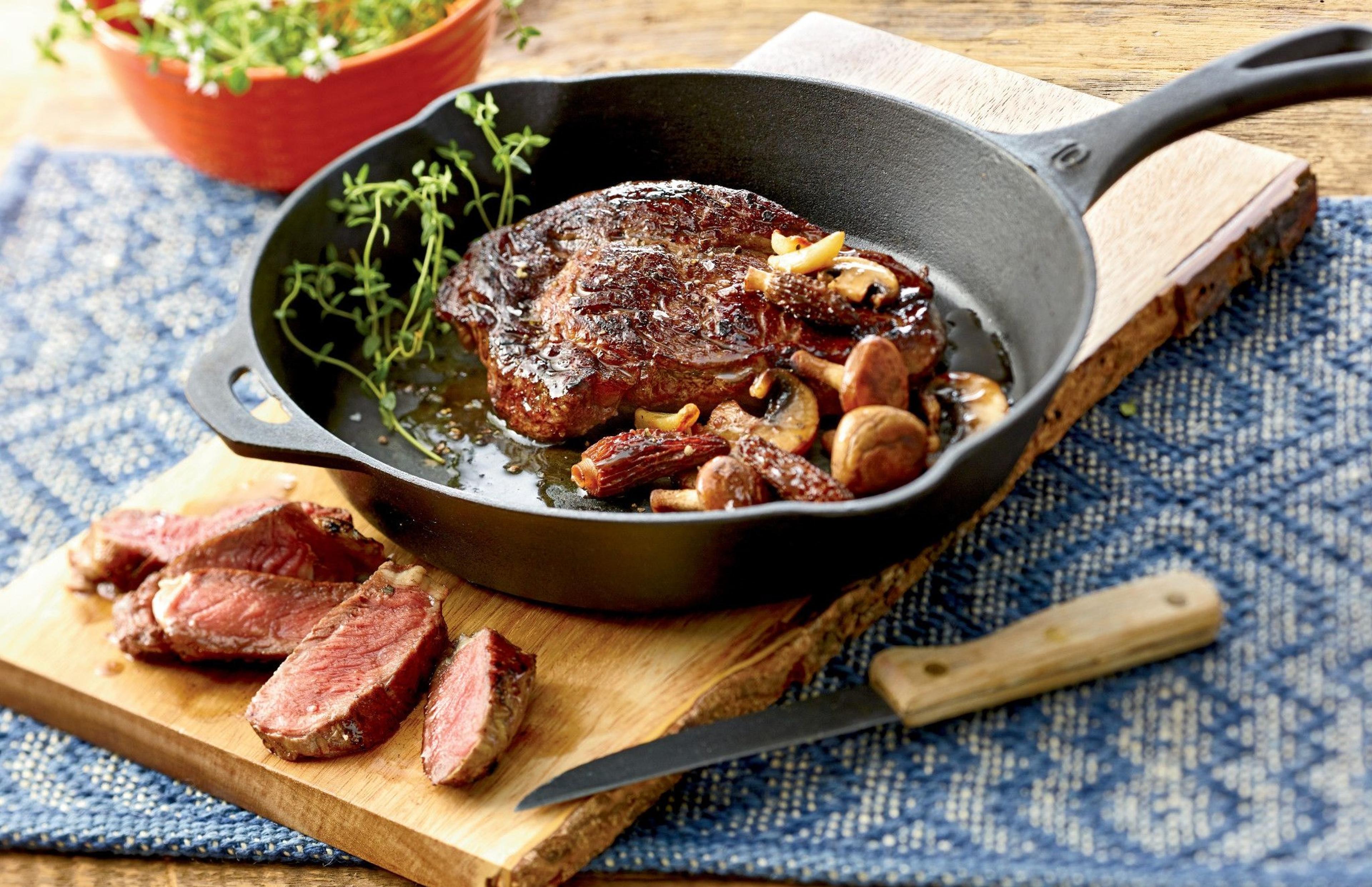 Organic ribeye steak in a cast iron pan.