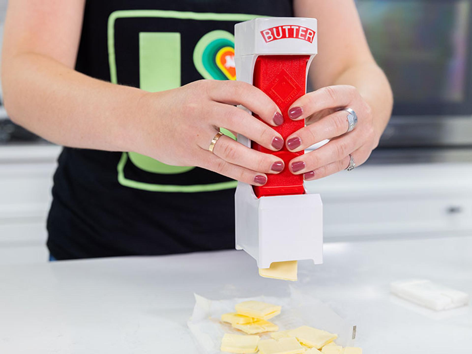 A woman uses a One-Click Butter Cutter to dispense butter.