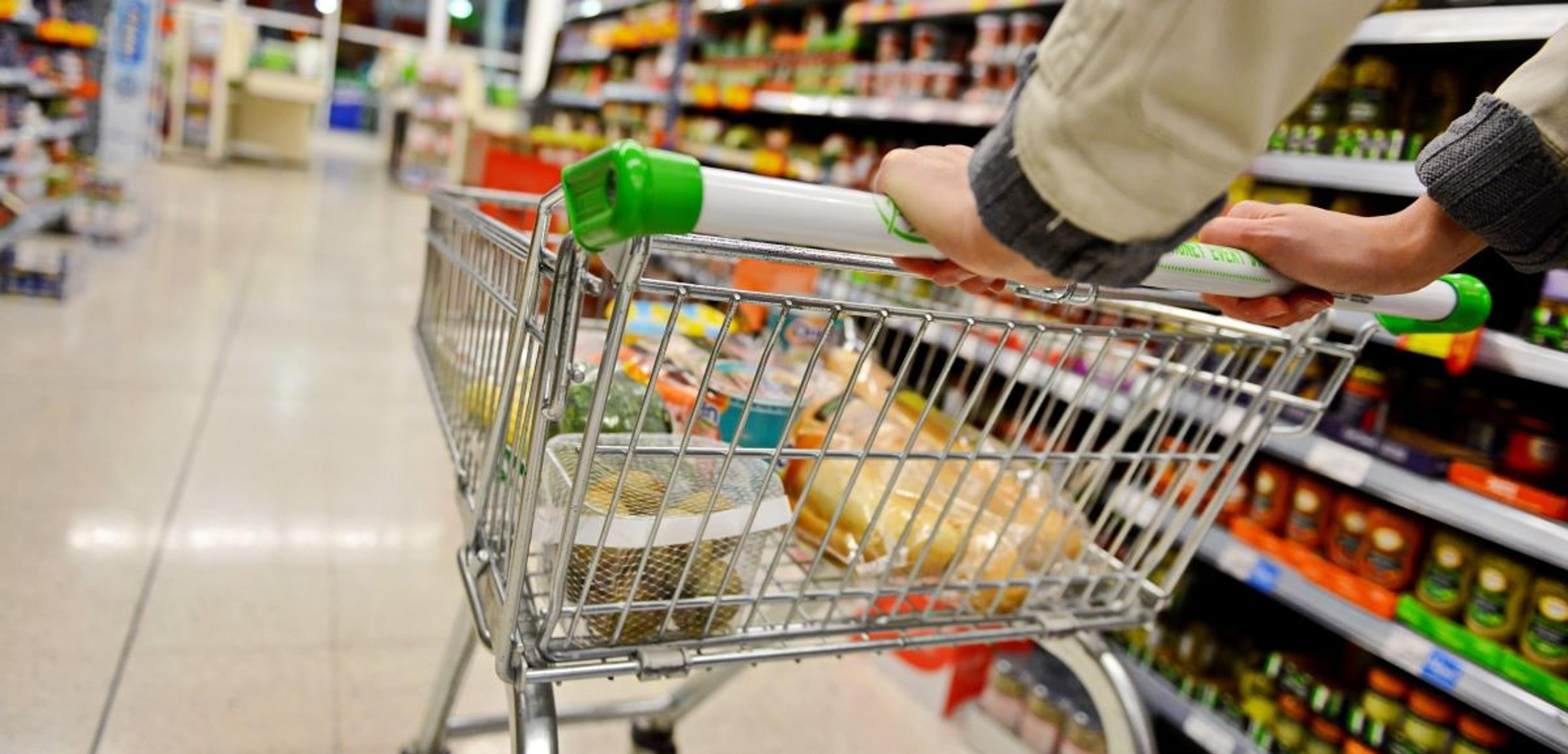 A man pushes a shopping cart through a grocery store.