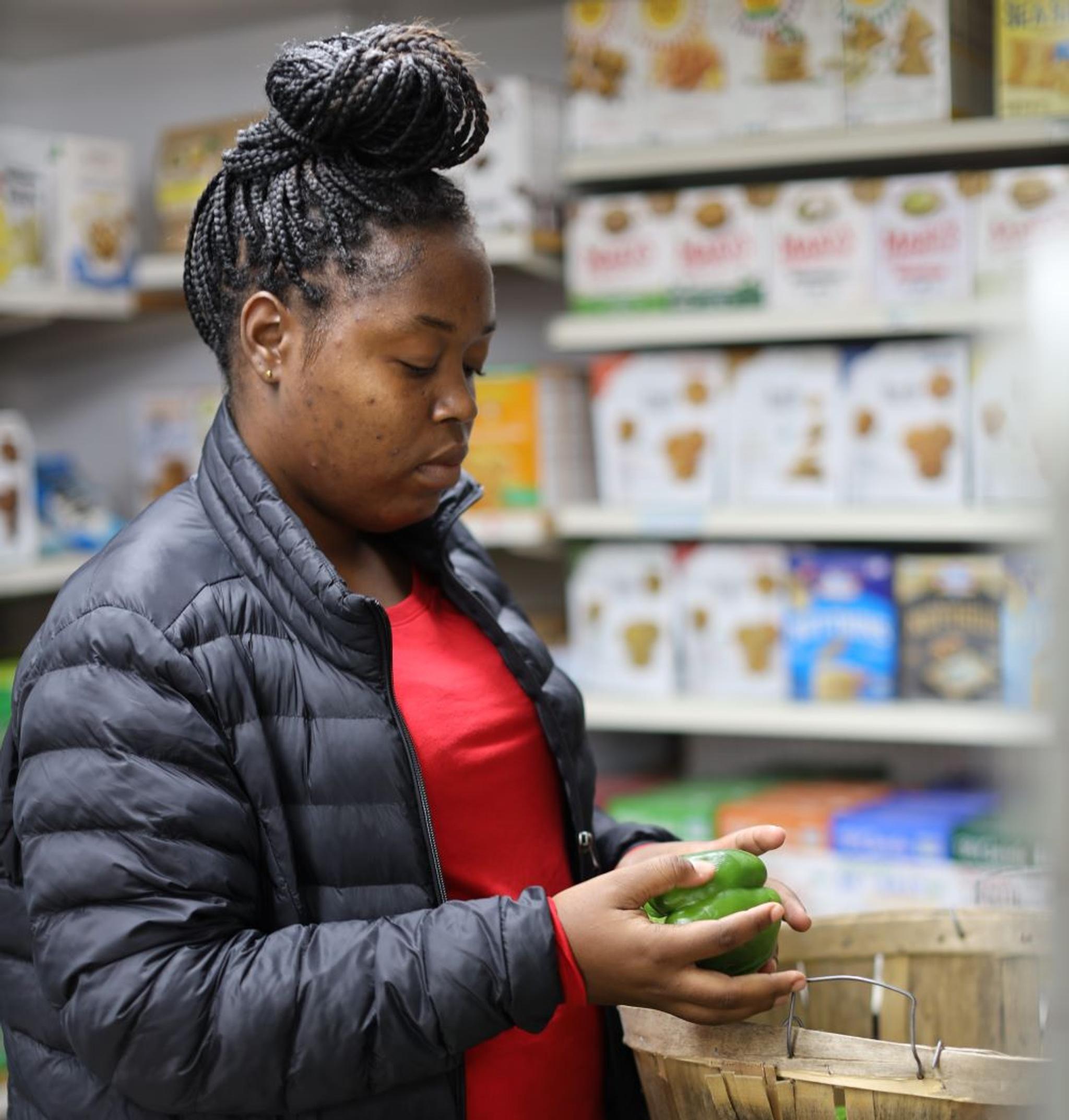 A woman sorts through bushel baskets of green peppers.