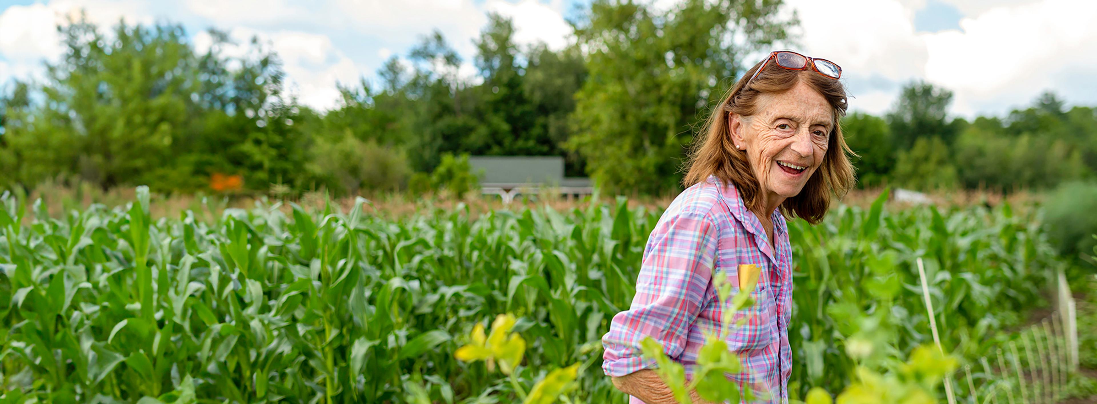 Farmer standing in corn field wearing glasses and smiling.