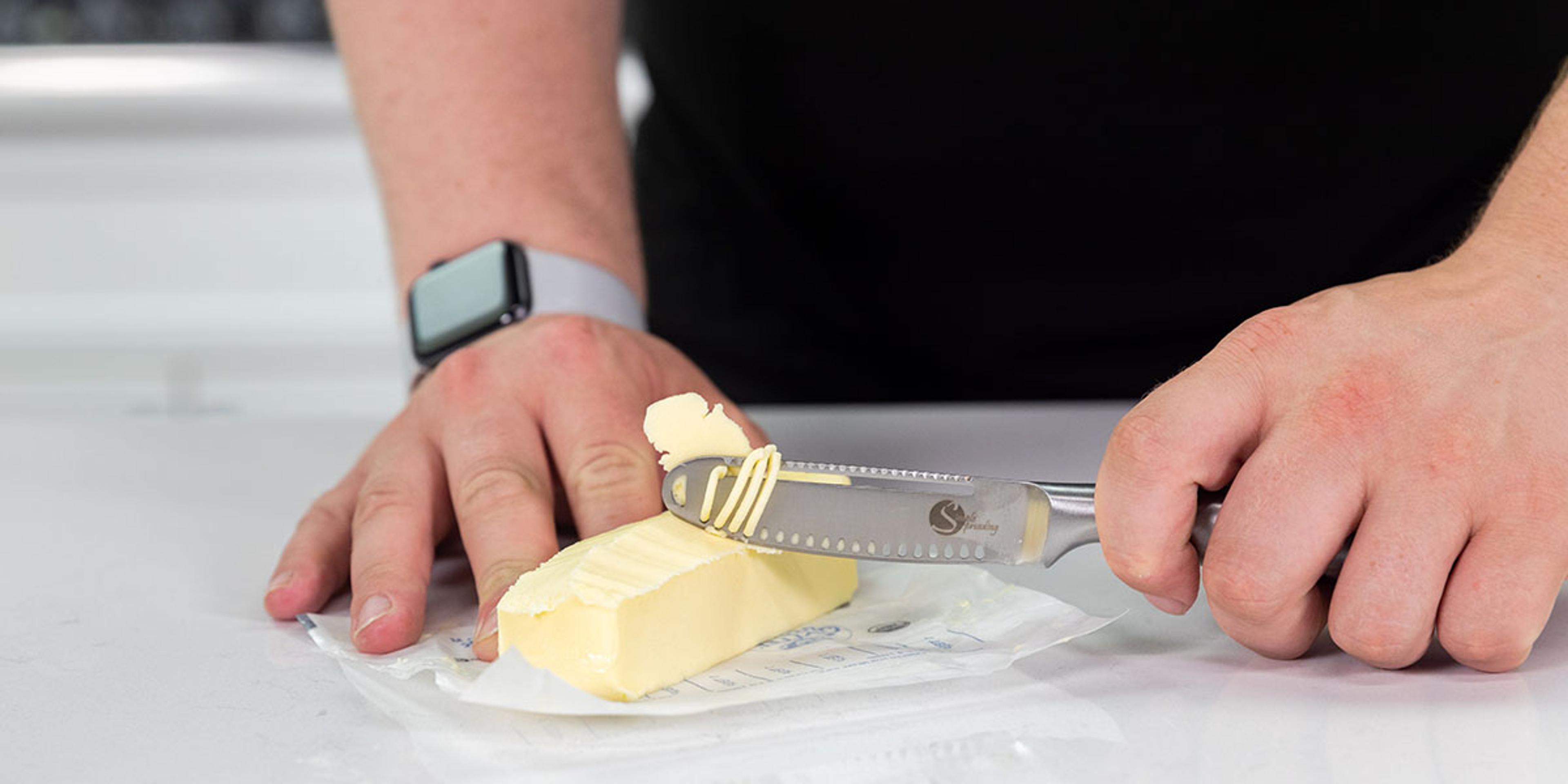A man uses a butter spreader and curler on organic butter.