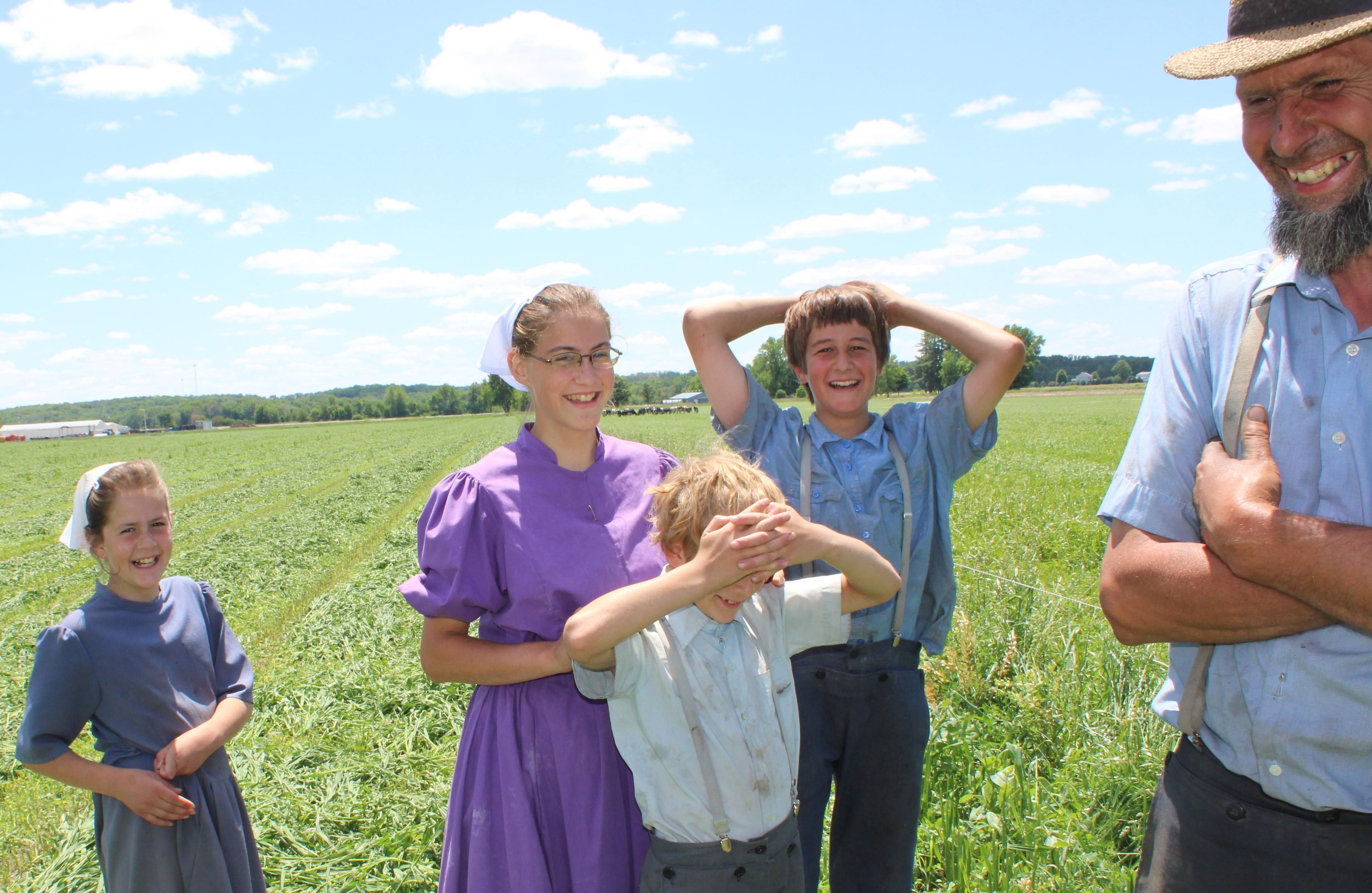 Miller family members laugh while standing in a field.