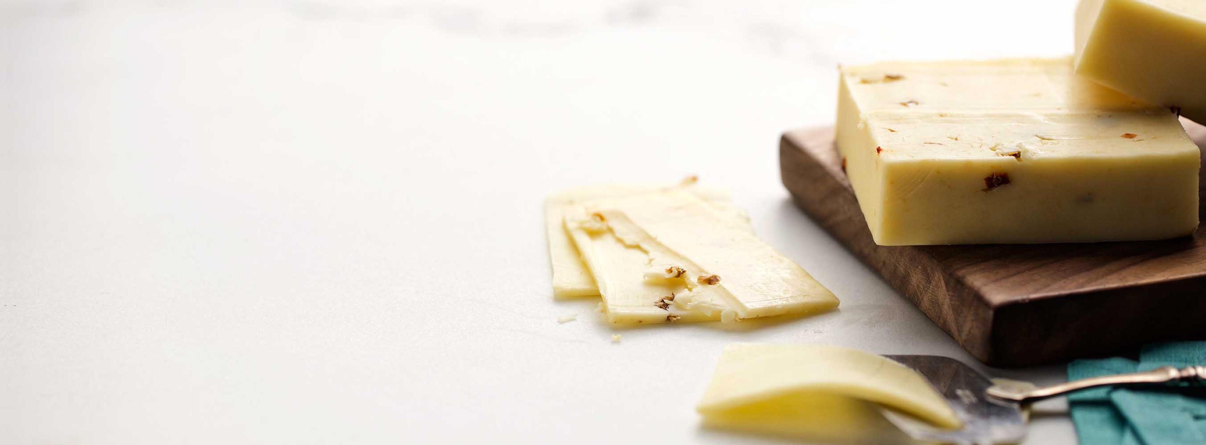 A block of pepperjack cheese on a wooden plate.