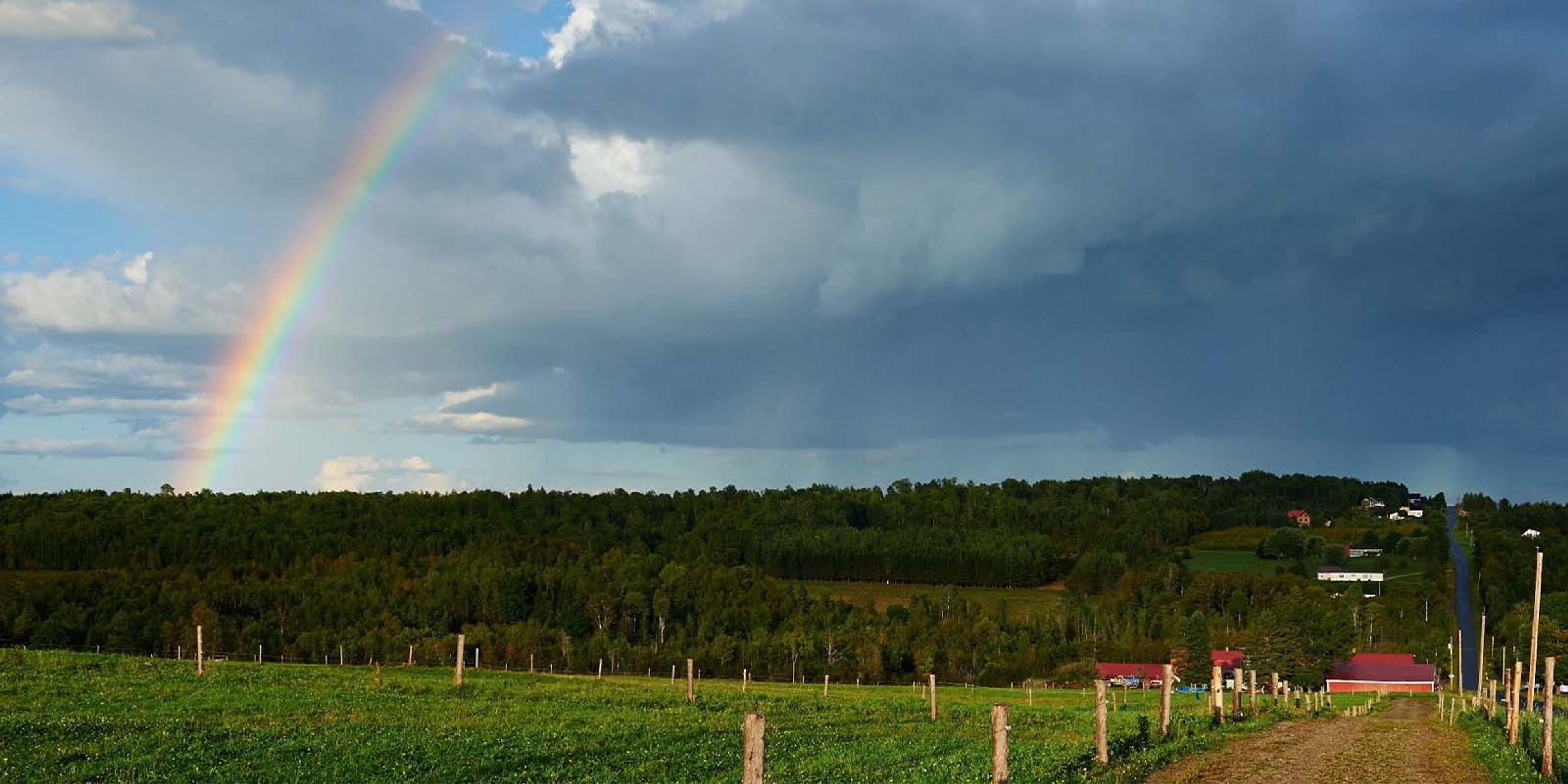 A rainbow and clouds are shown in the landscape of the Chase farm in Maine.