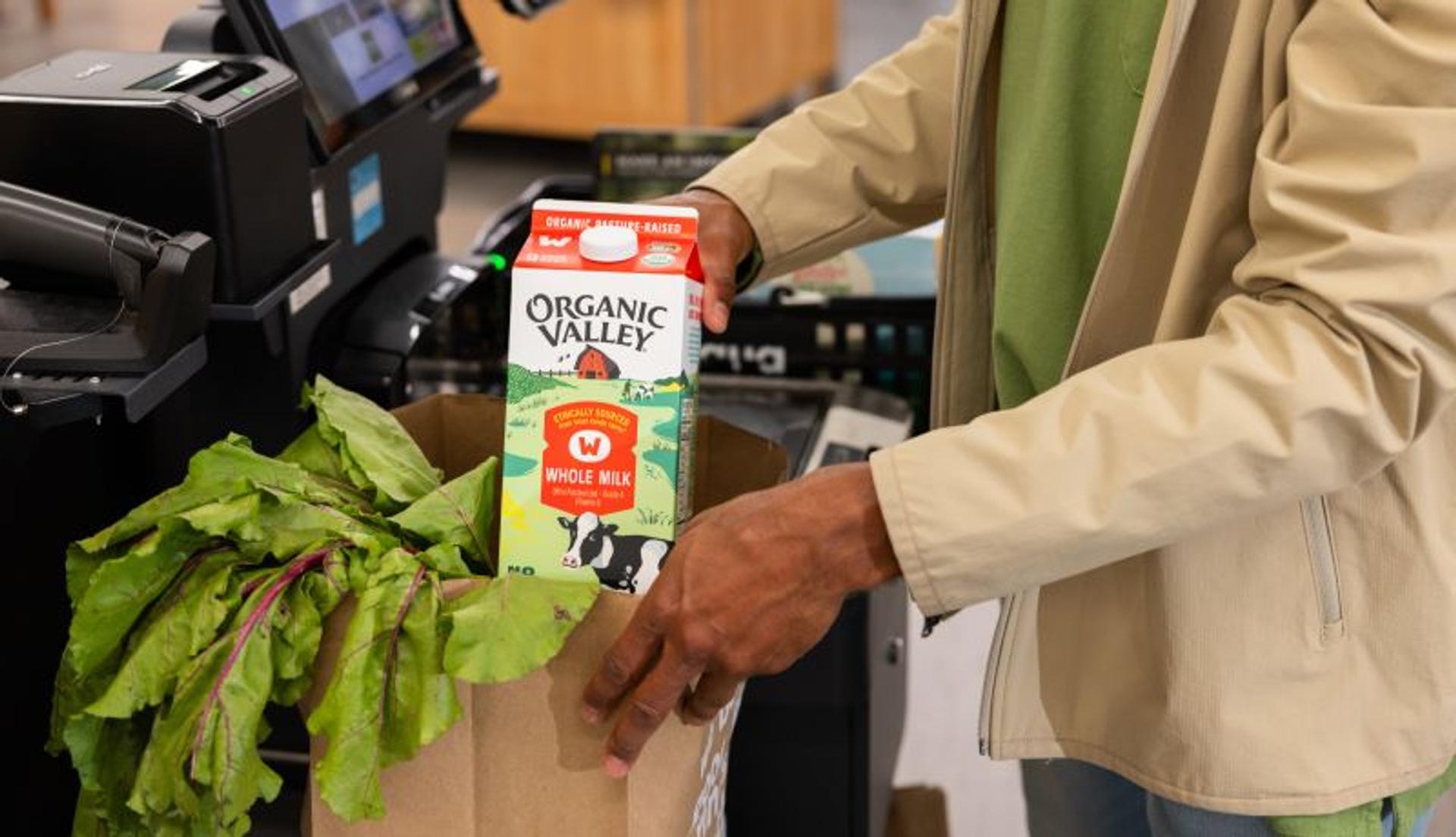 A man put Organic Valley Whole Milk in a grocery bag.