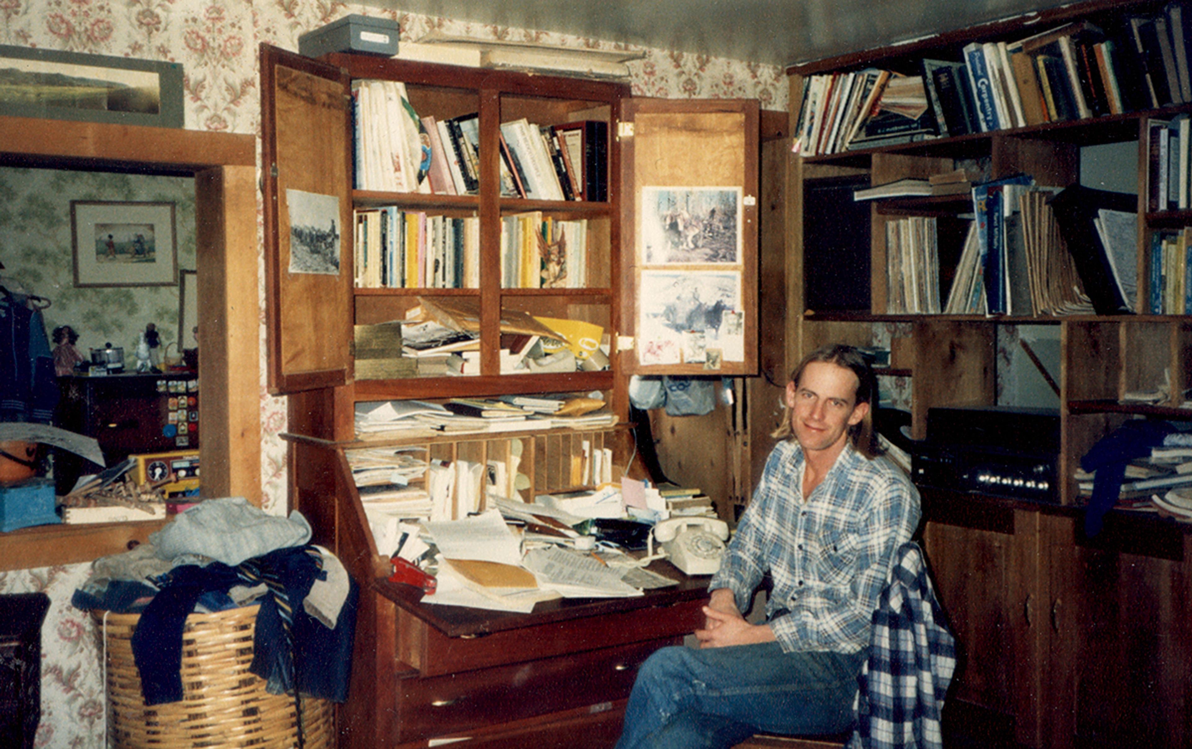 Former Organic Valley CEO George Siemon takes a break for a photo. His disheveled, paper-filled desk in the background.