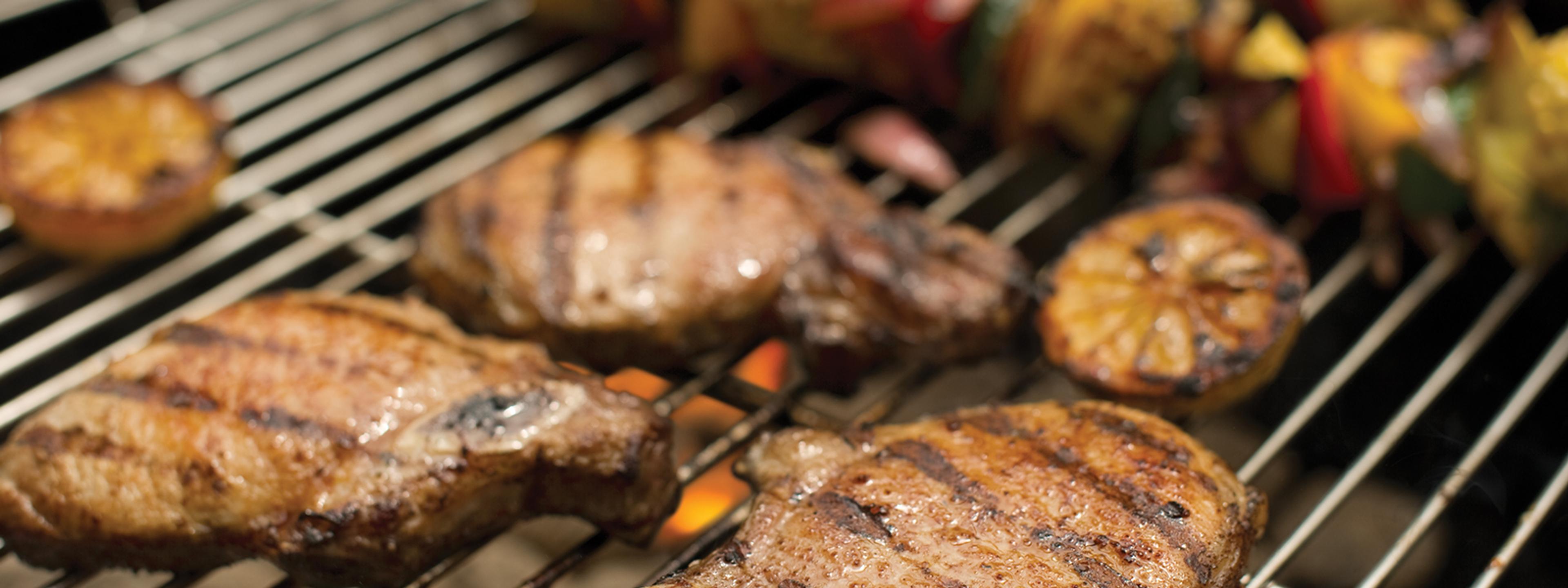 Organic pork chops cooking on a grill