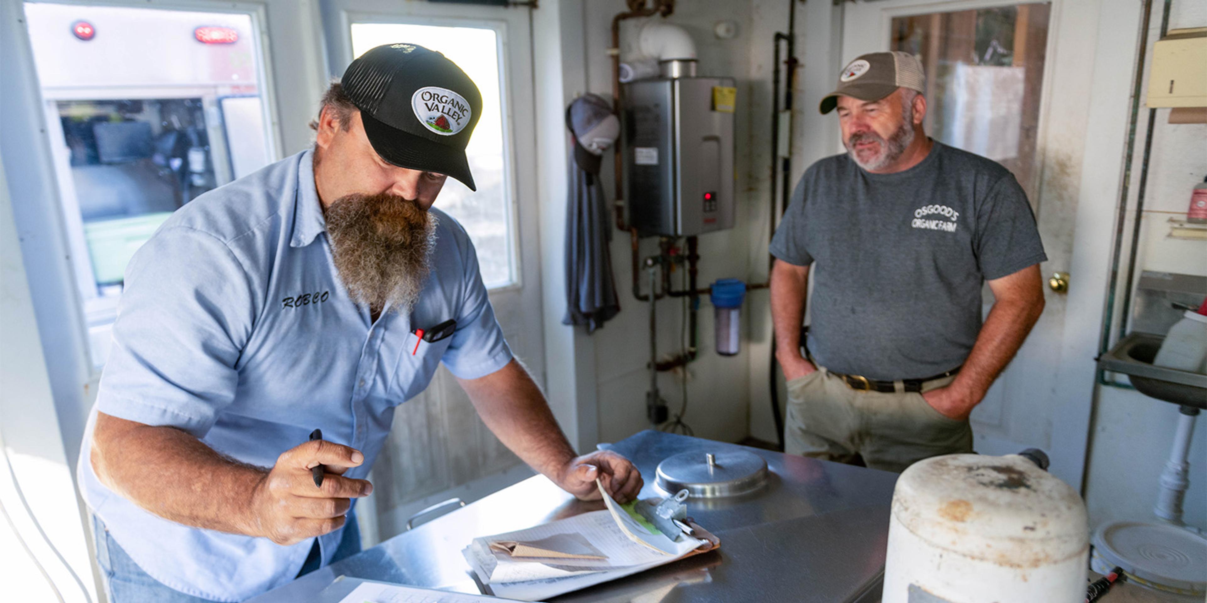 A milk truck driver and farmer in a milkhouse.