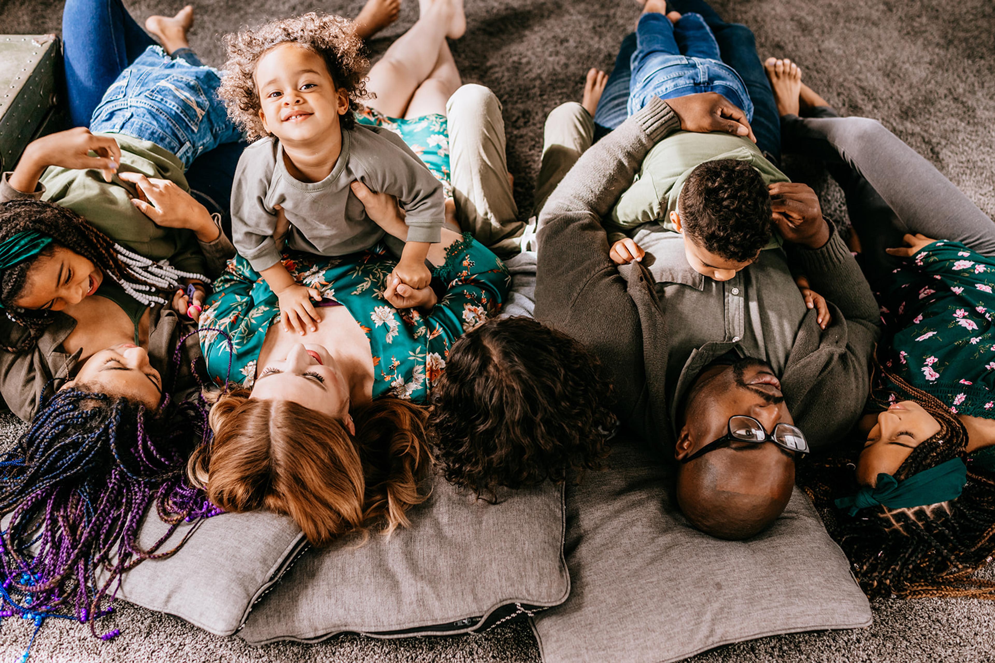 Megan Joy Yancy and family lay on the floor together, smiling at the camera.