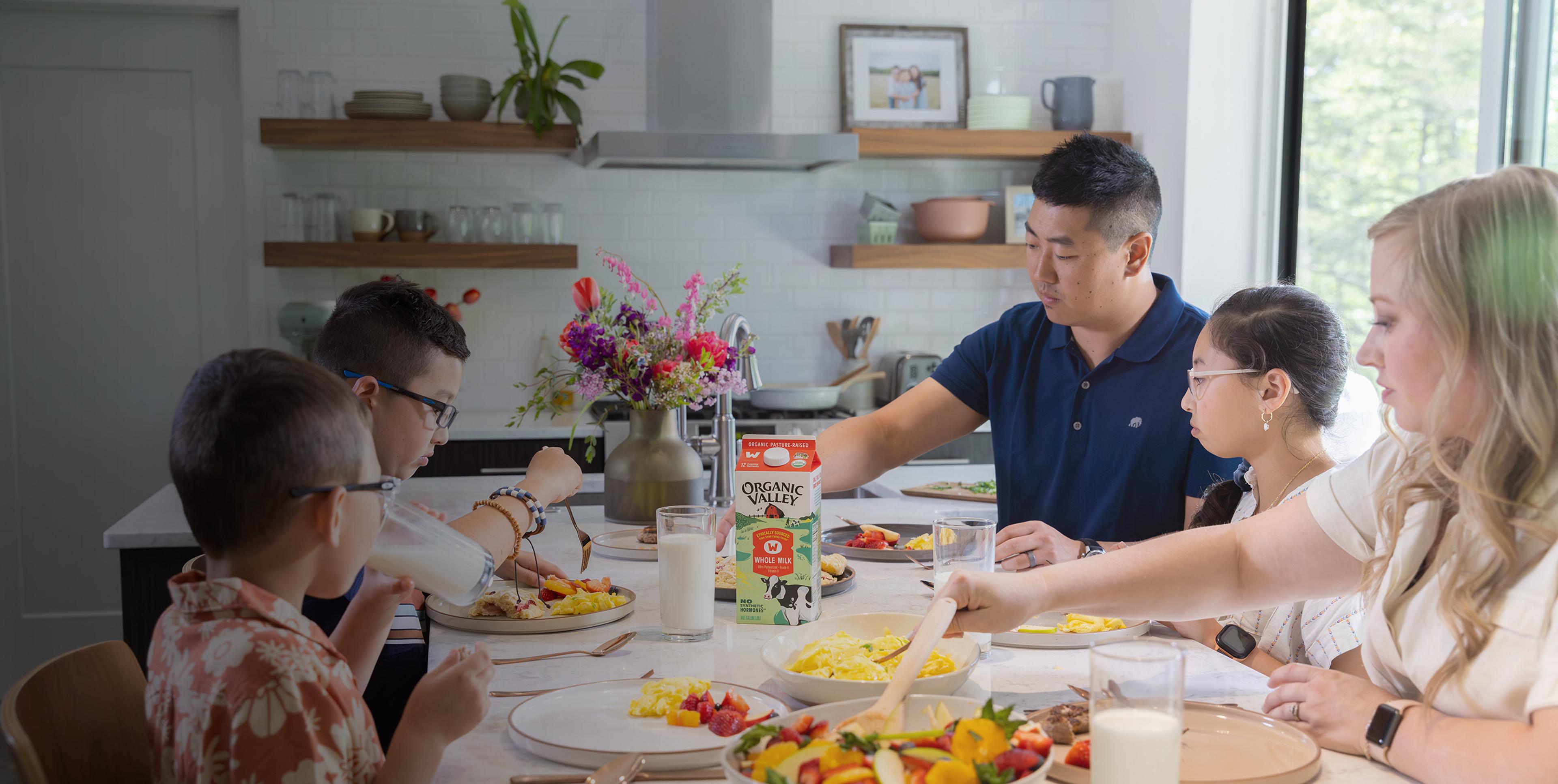 A family sitting at a table with food and Organic Valley milk.