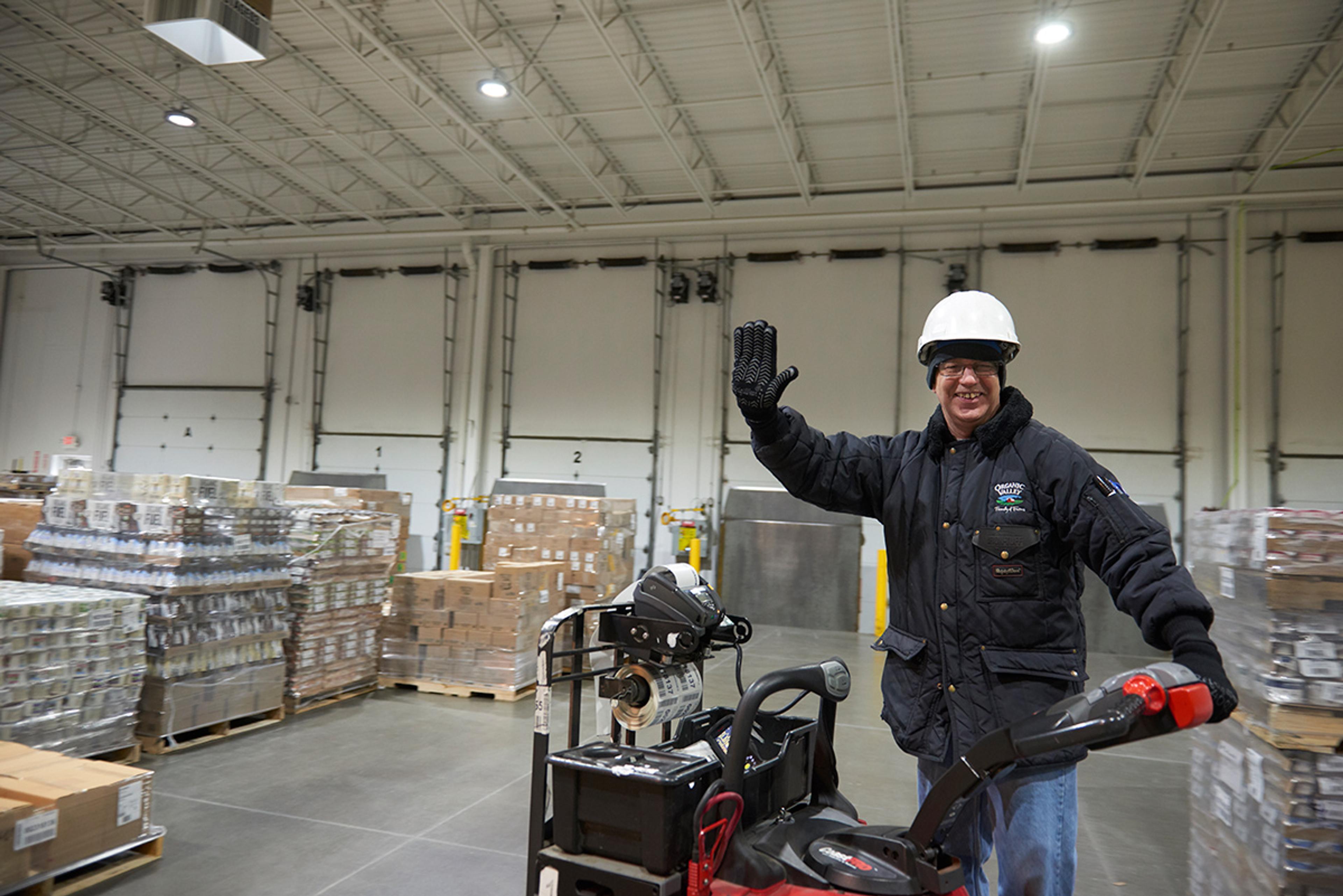 Organic Valley employee waves on a warehouse cart at the distribution center in Cashton, Wisconsin.