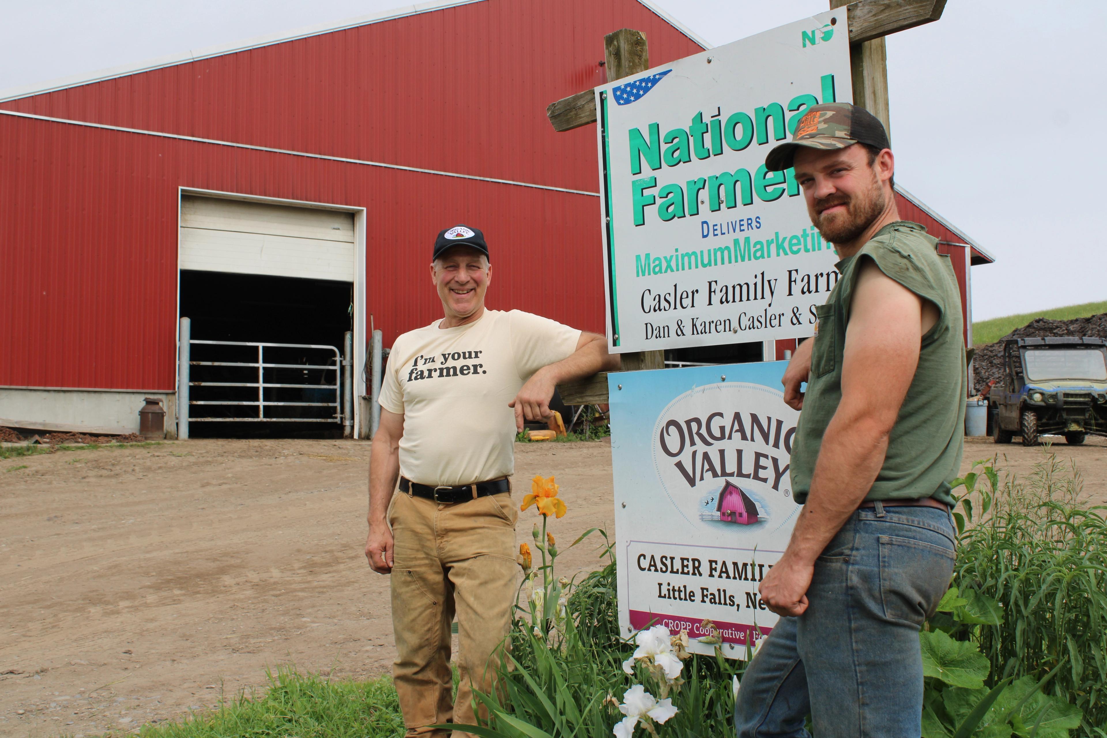 Dan and Jeremiah Casler stand in front of an Organic Valley sign. 