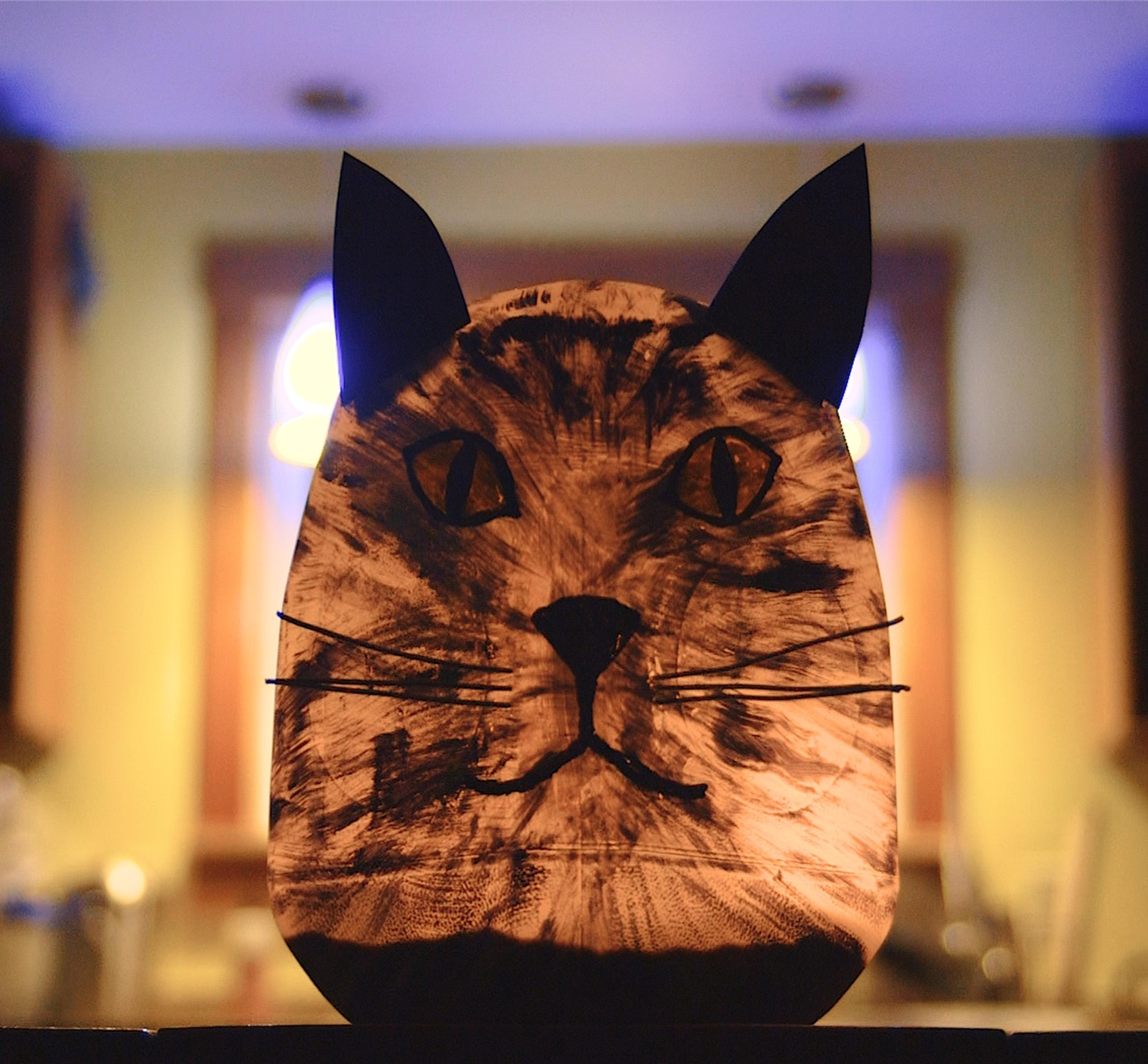 A completed and illuminated milk jug luminary with a cat face and ears.