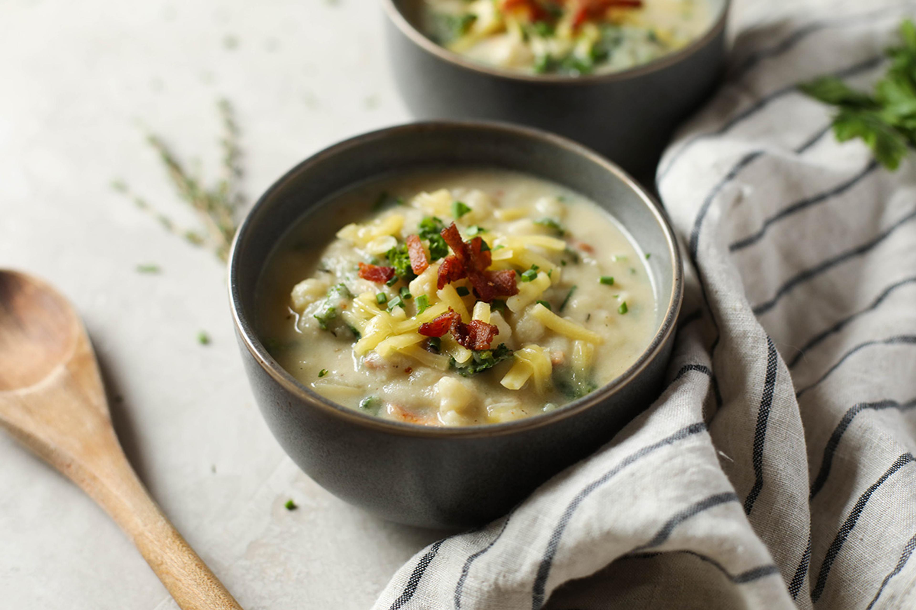 Loaded cheesy cauliflower soup topped with chives, shredded cheese, and bacon crumbles.