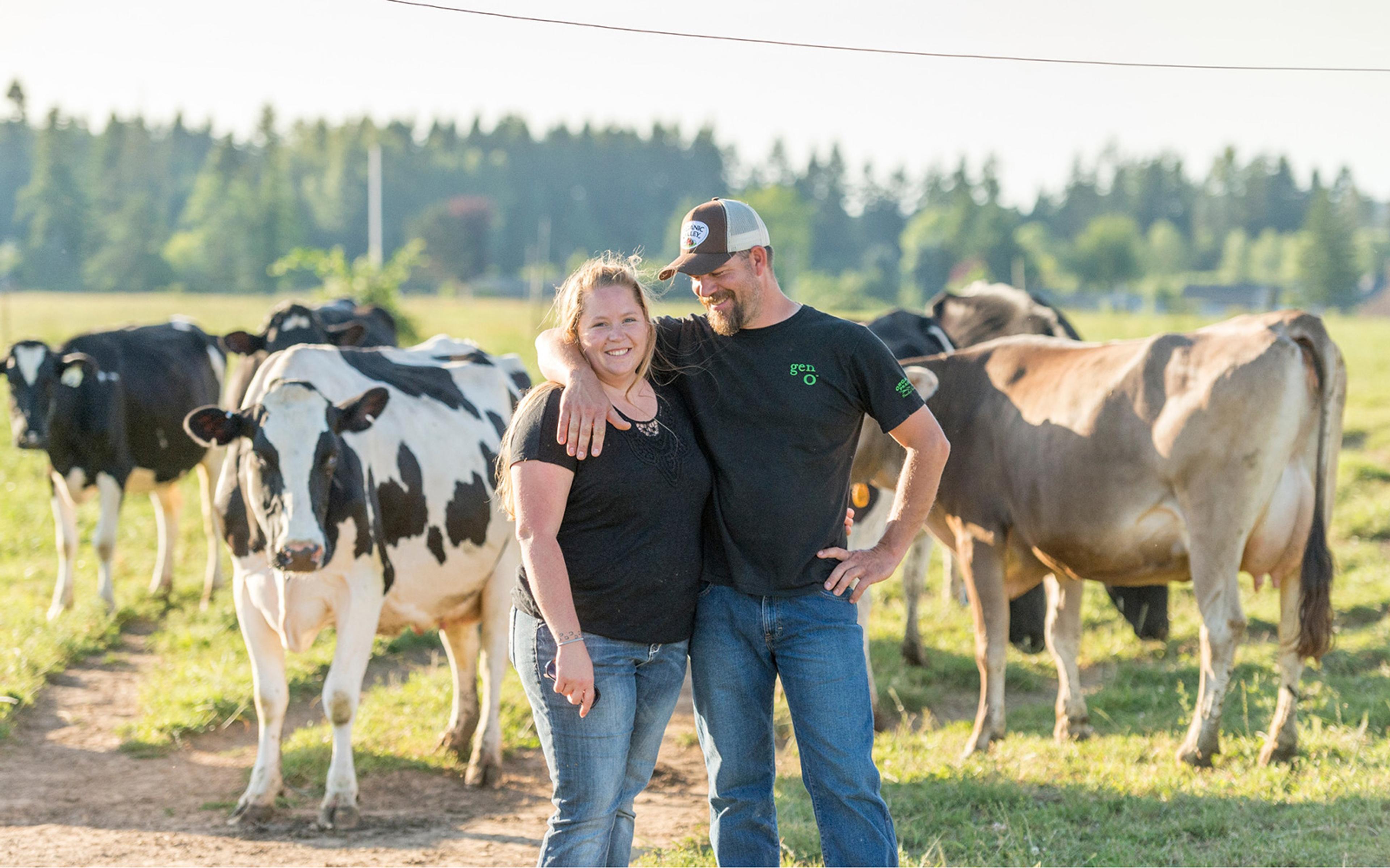 Melissa Collman with her spouse, Andy, standing in front of their herd of Holsteins.