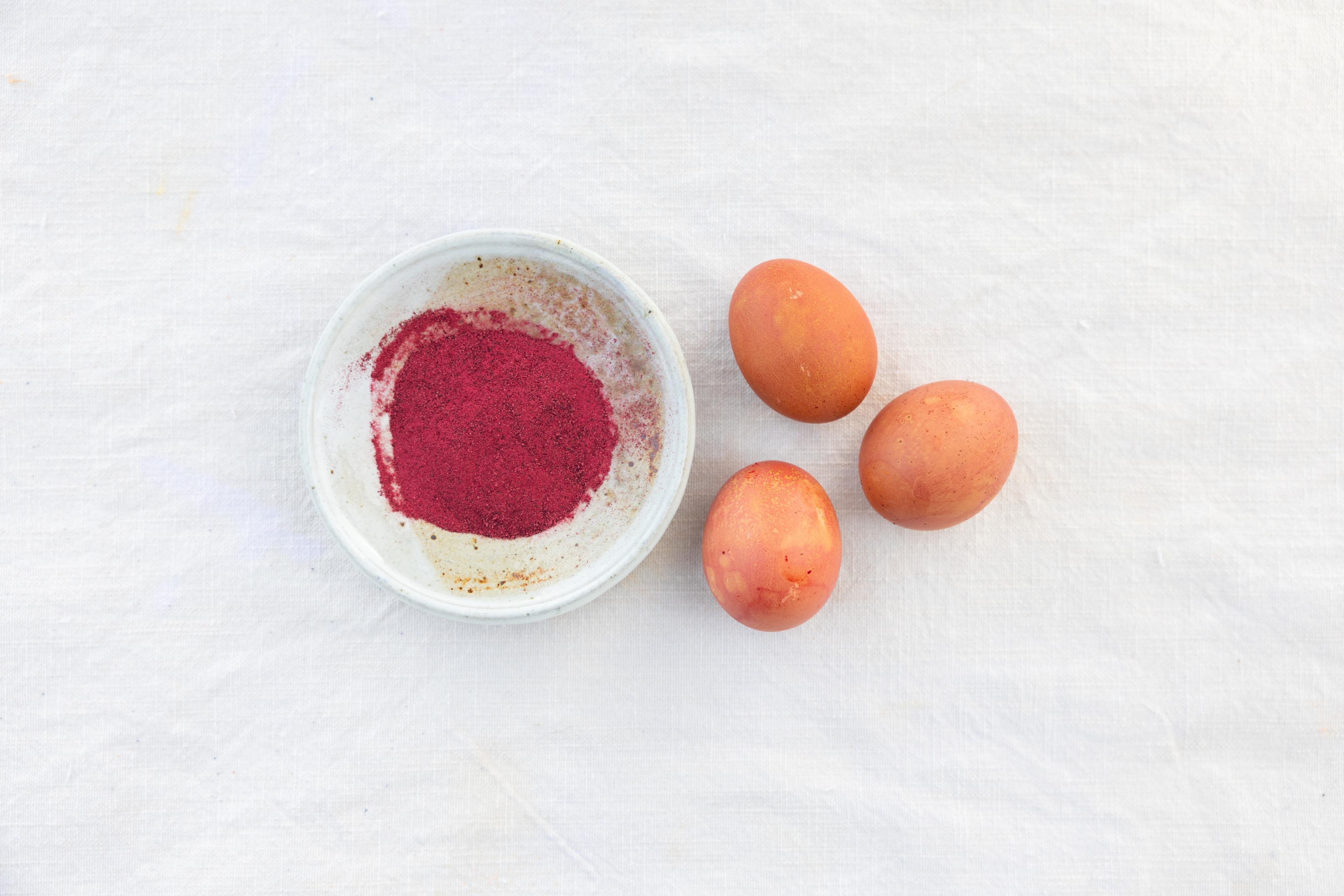 Beet root powder next to colored hard-boiled eggs.