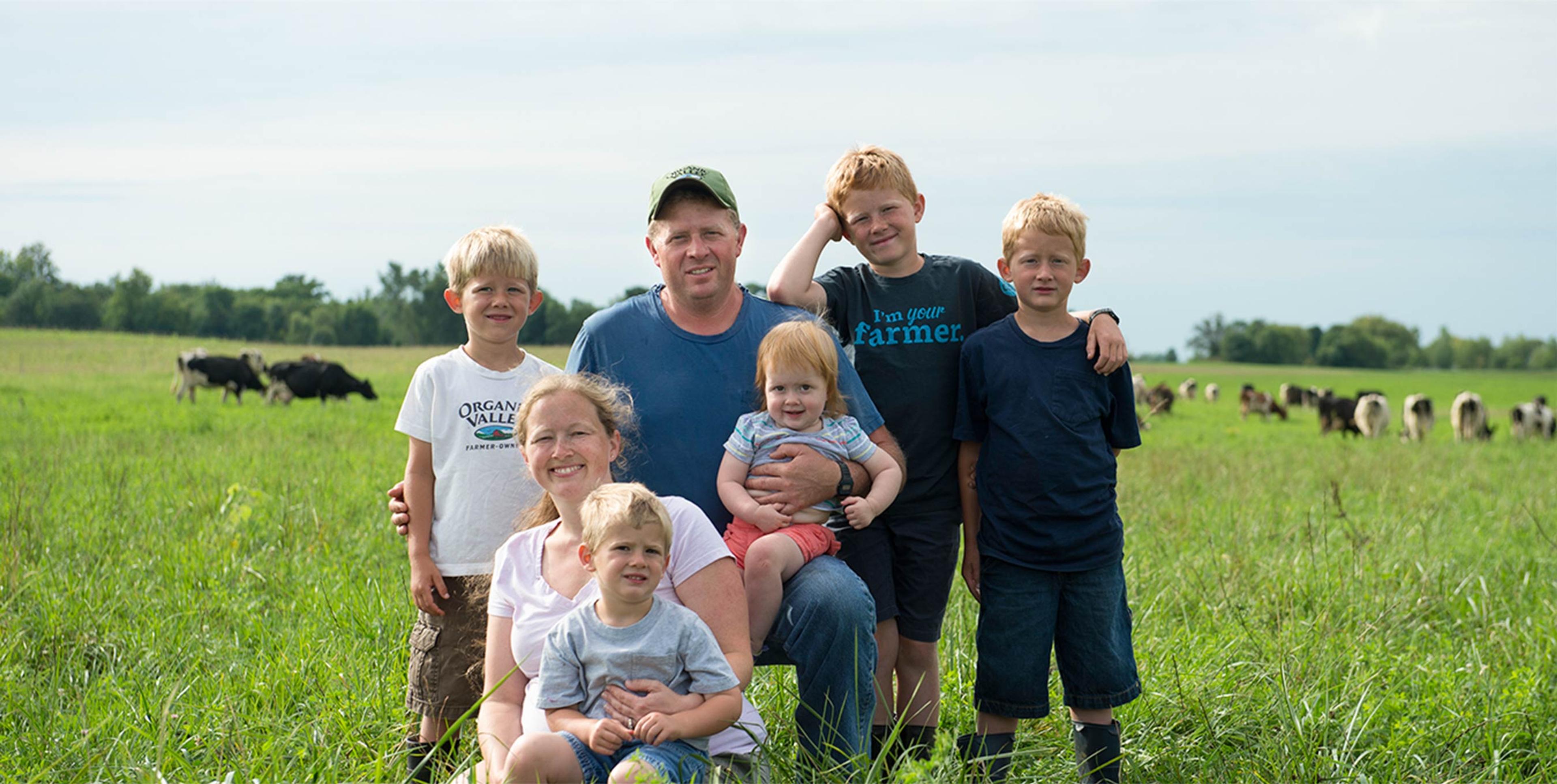 The Elsenpeter family at Valley View Dairy in Maple Lake, MN with cows grazing in the background.