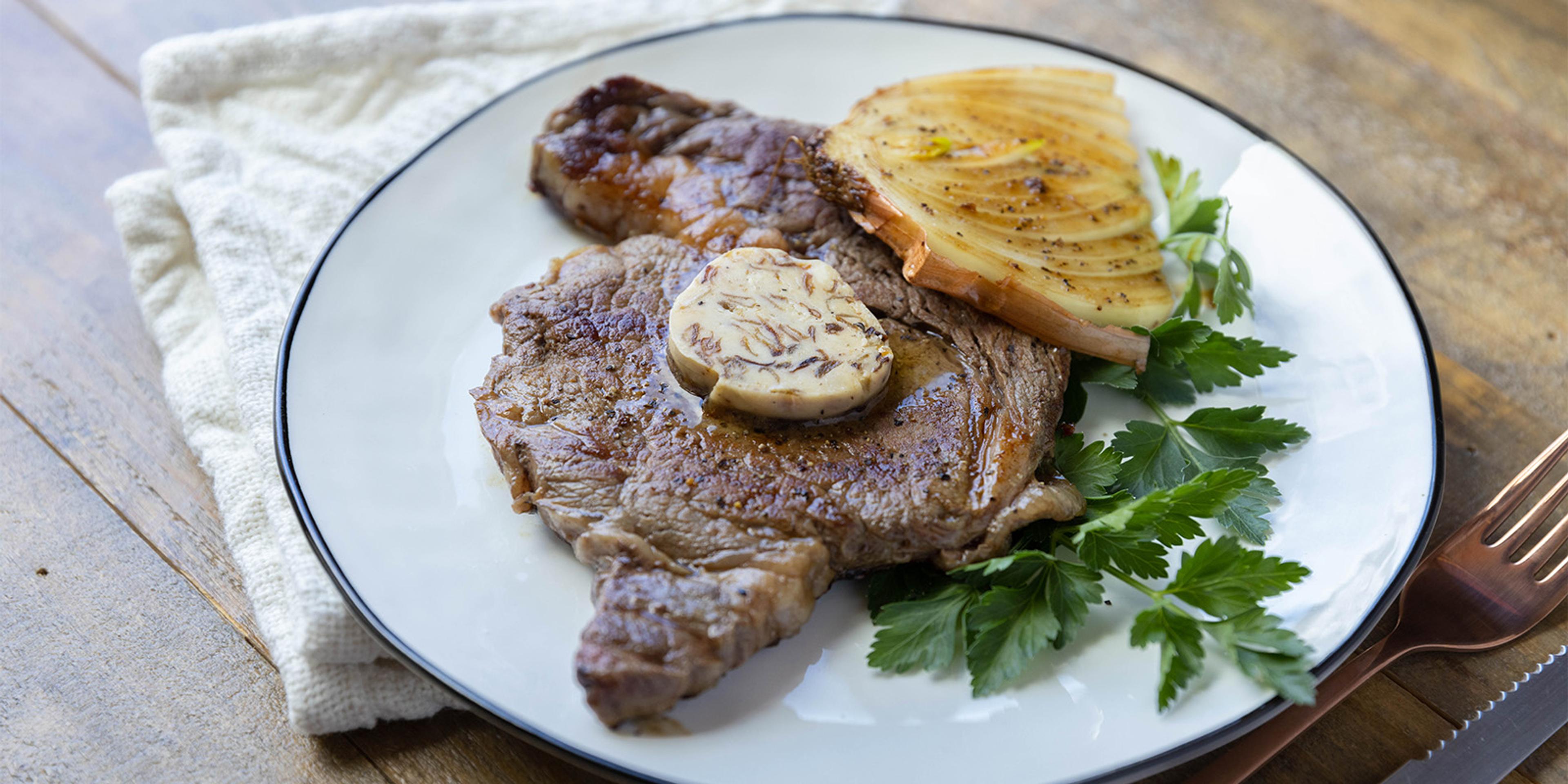 Caramelized Onion Compound Butter on top of a steak garnished with parsley.
