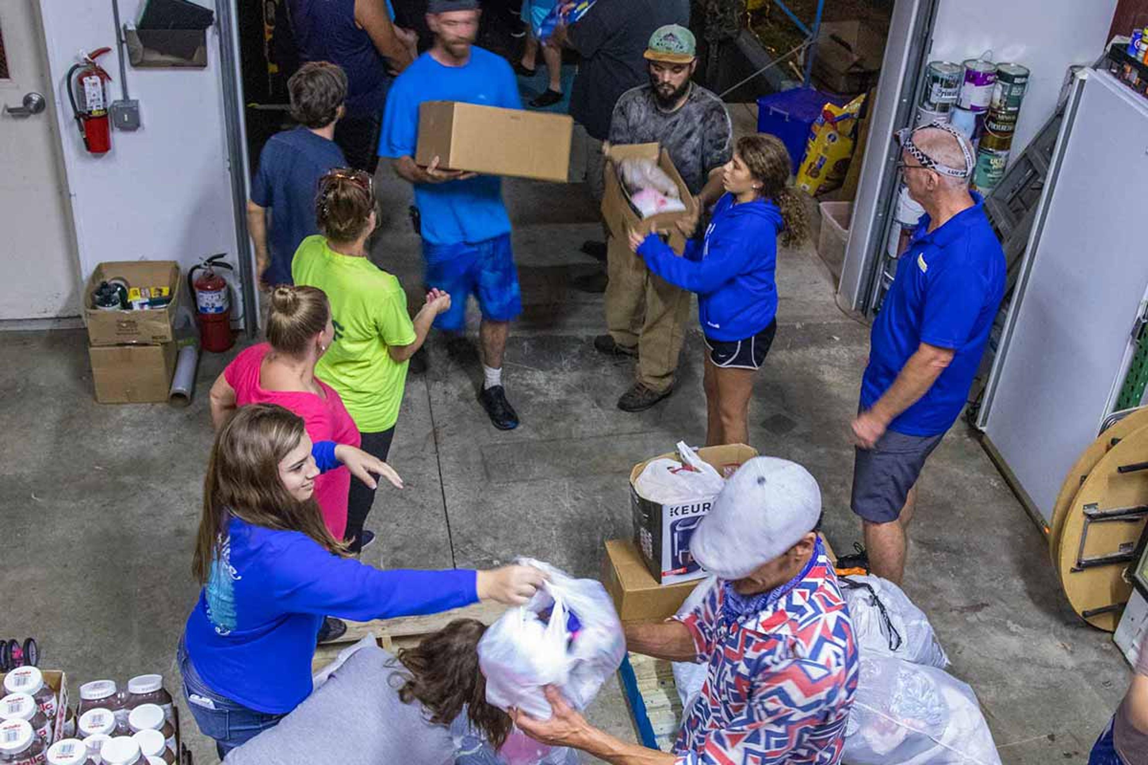 High-angle view looking down on a group of disaster relief workers unloading a truck full of food and supplies into a warehouse.