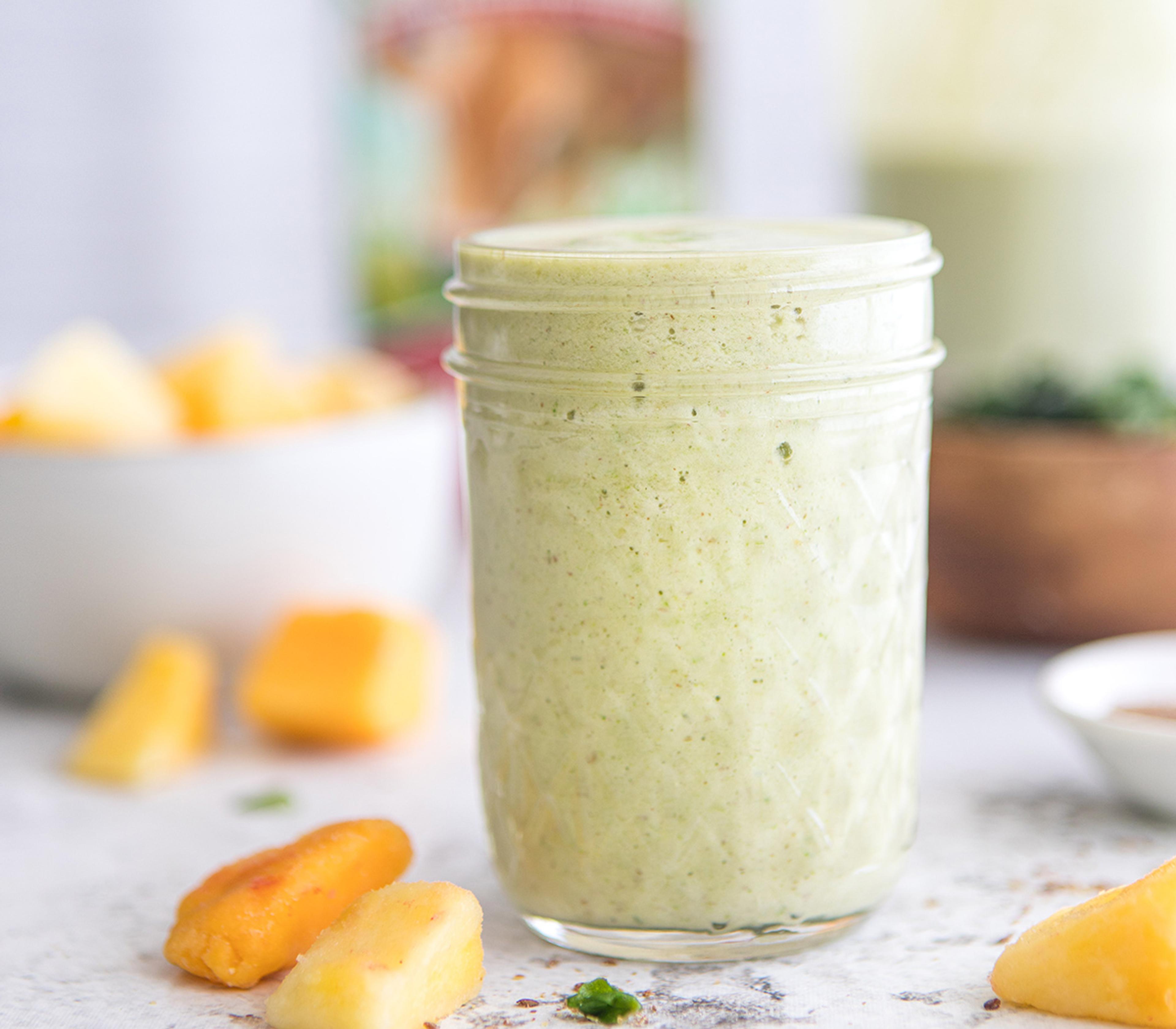 A mason jar is filled with this Kick-Grass Tropical Green smoothie recipe.