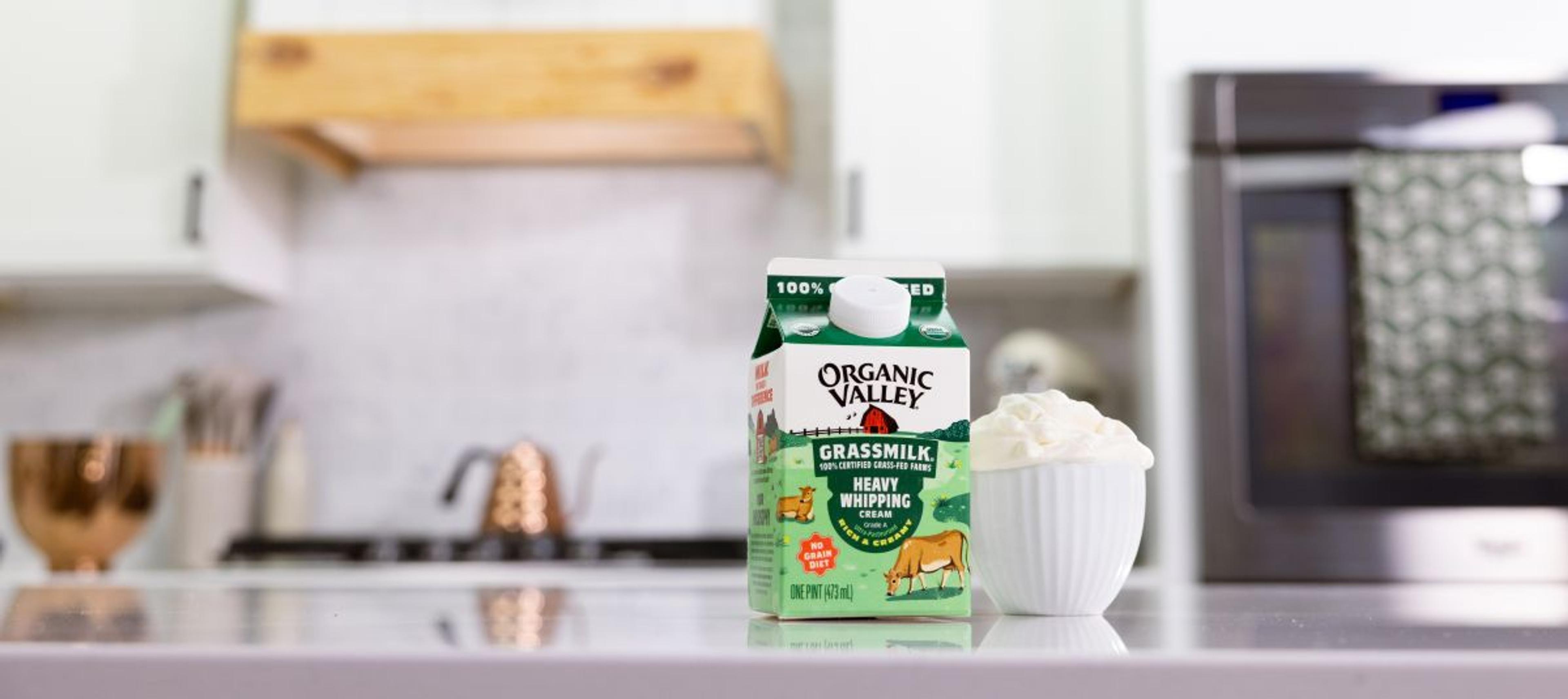 A carton of Organic Valley® Grassmilk Heavy Whipping Cream on a kitchen island next to a bowl of whipped cream.