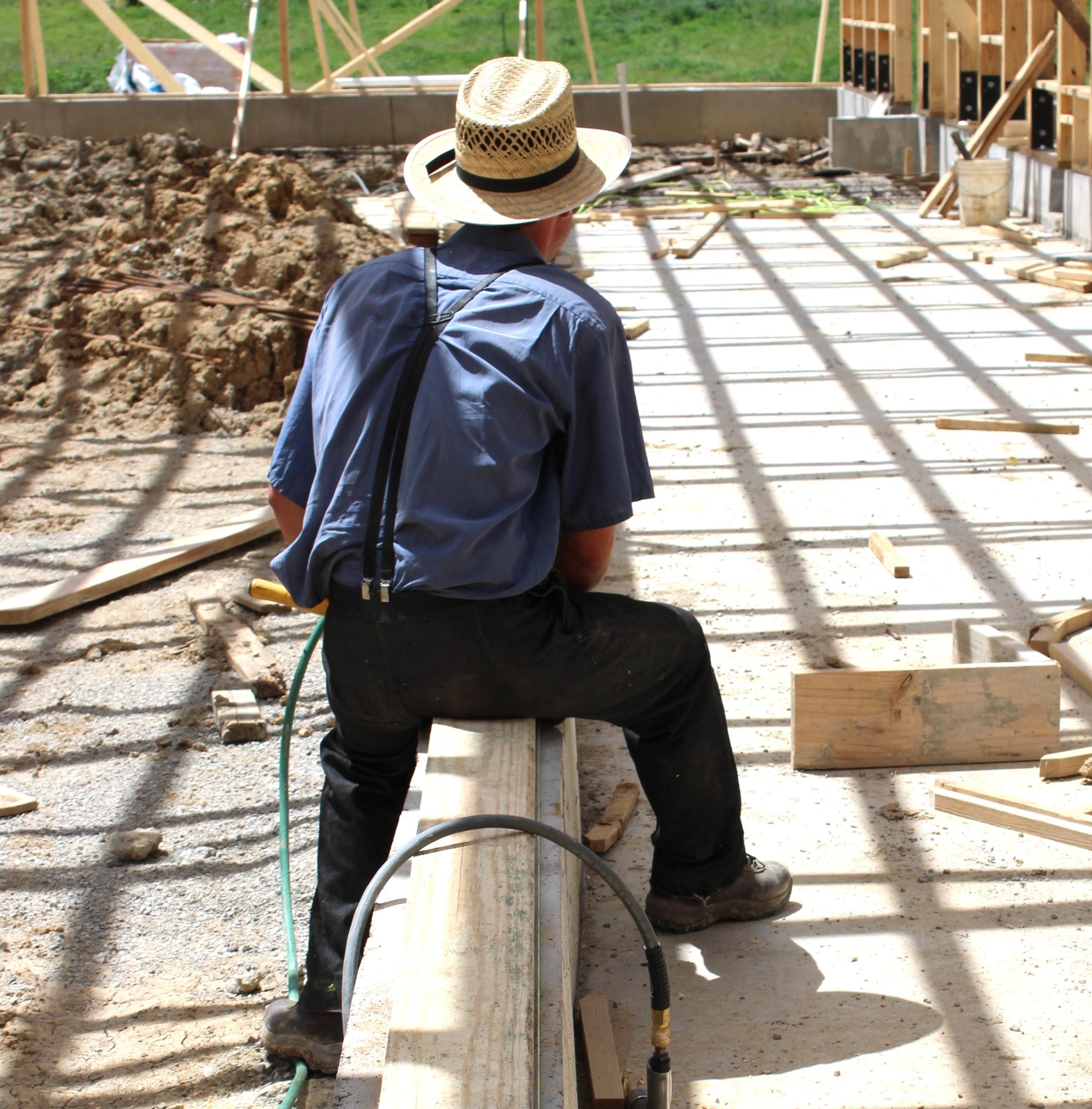 A man sits and works on a new barn.