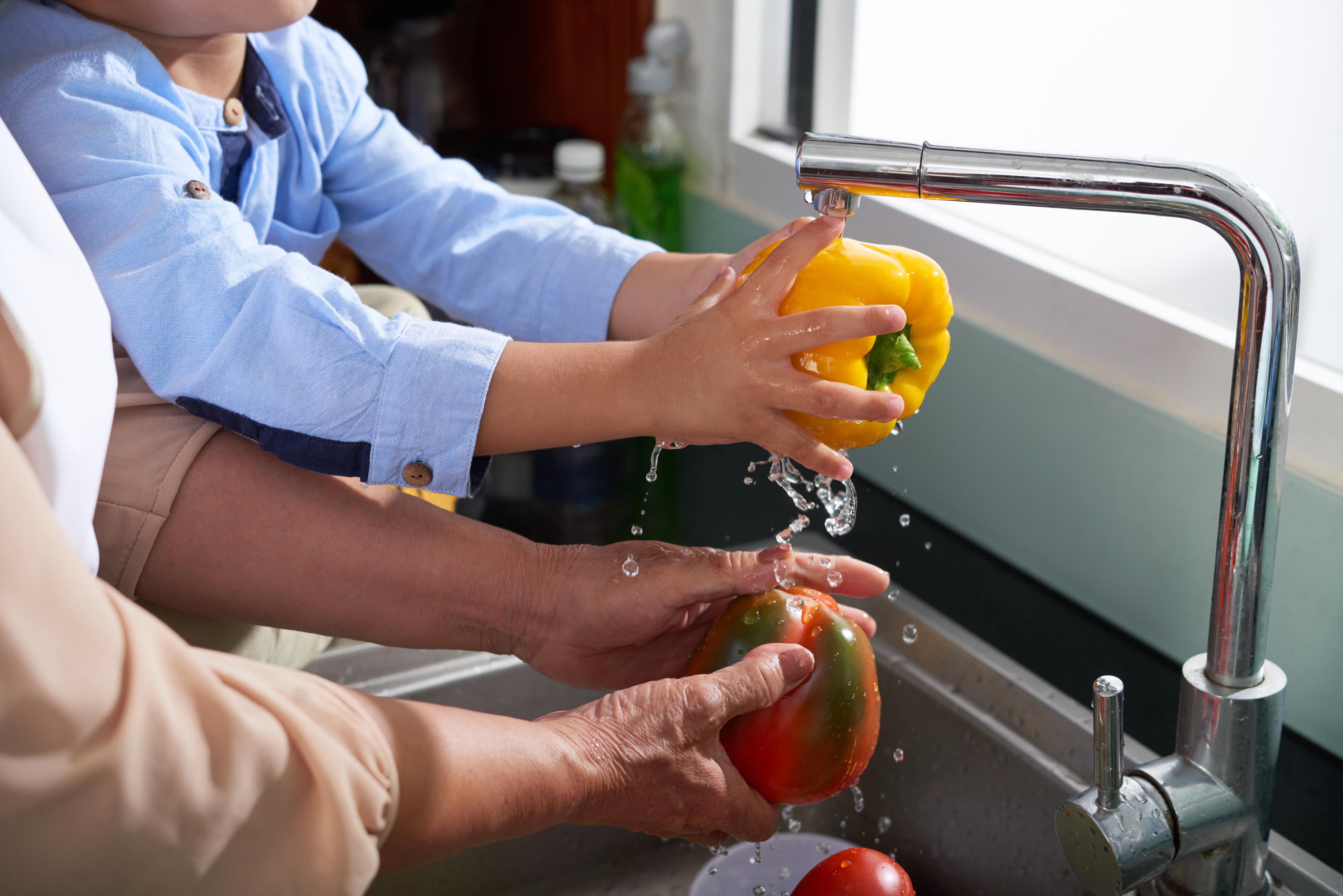 Washing bell peppers in the sink.